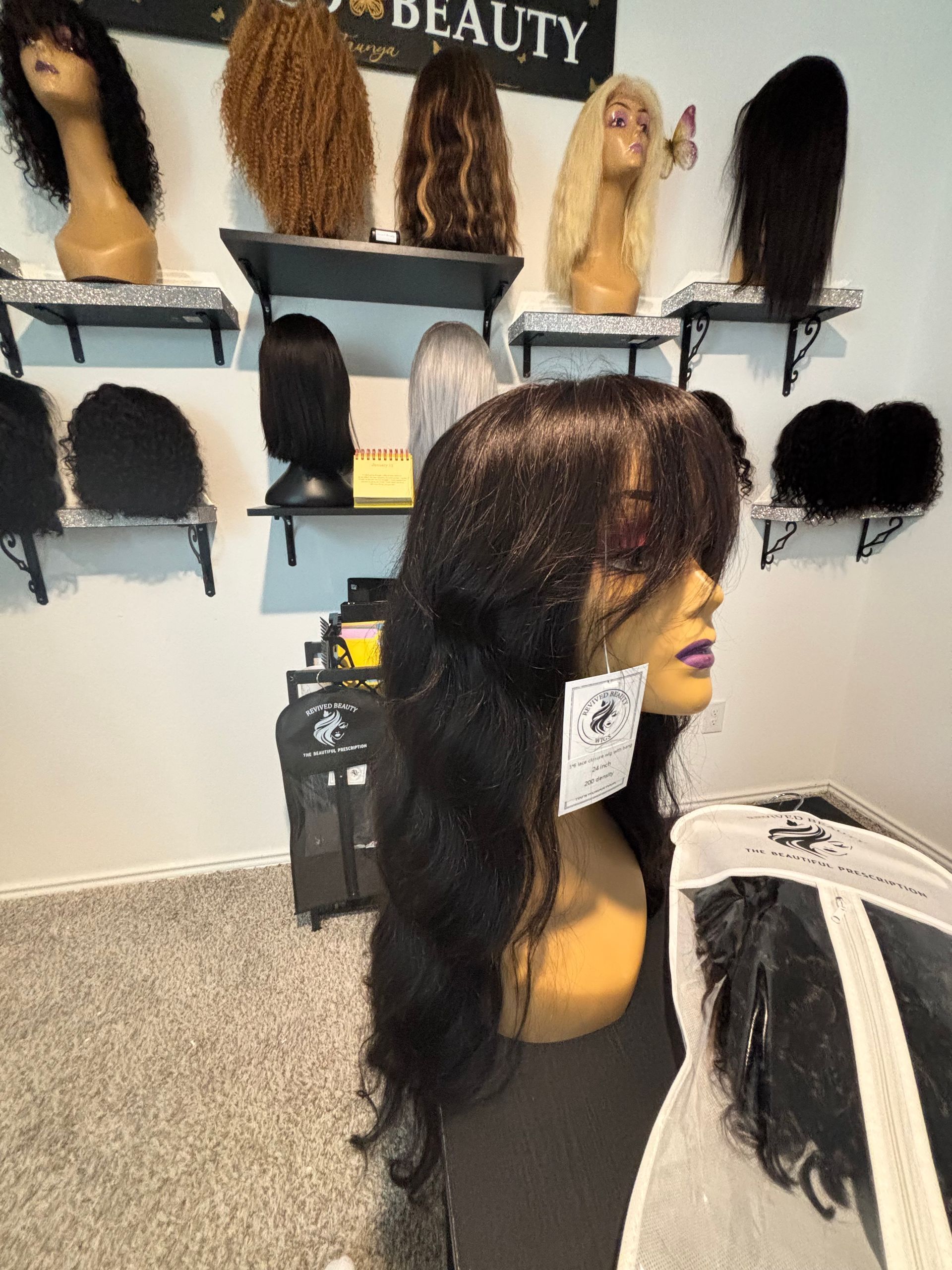 A mannequin with a long, wavy black wig with bangs, in a beauty store with various wigs on display. A mannequin with a long, wavy black wig with bangs, in a beauty store with various wigs on display.