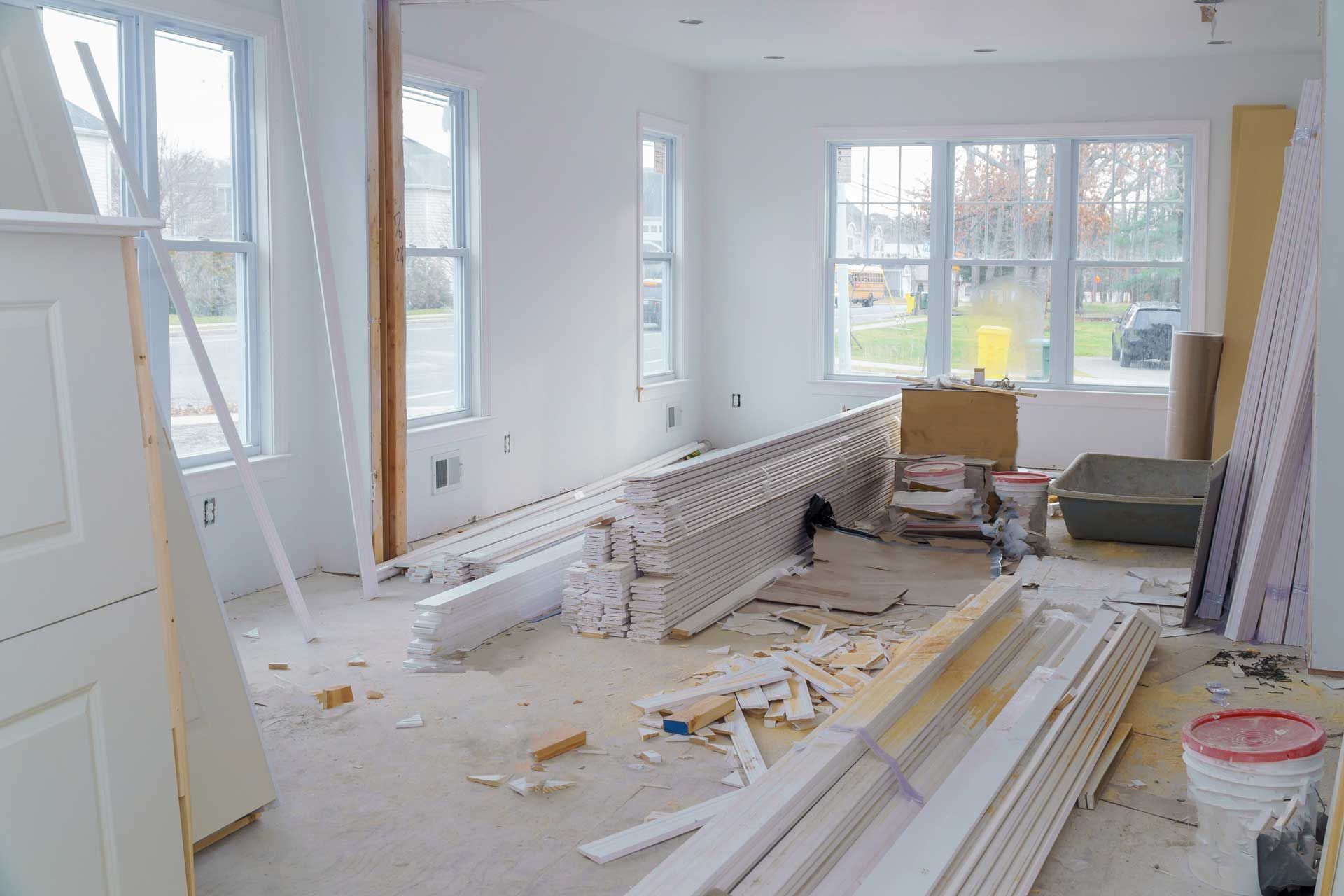 A living room in a house under construction with a lot of wood on the floor.