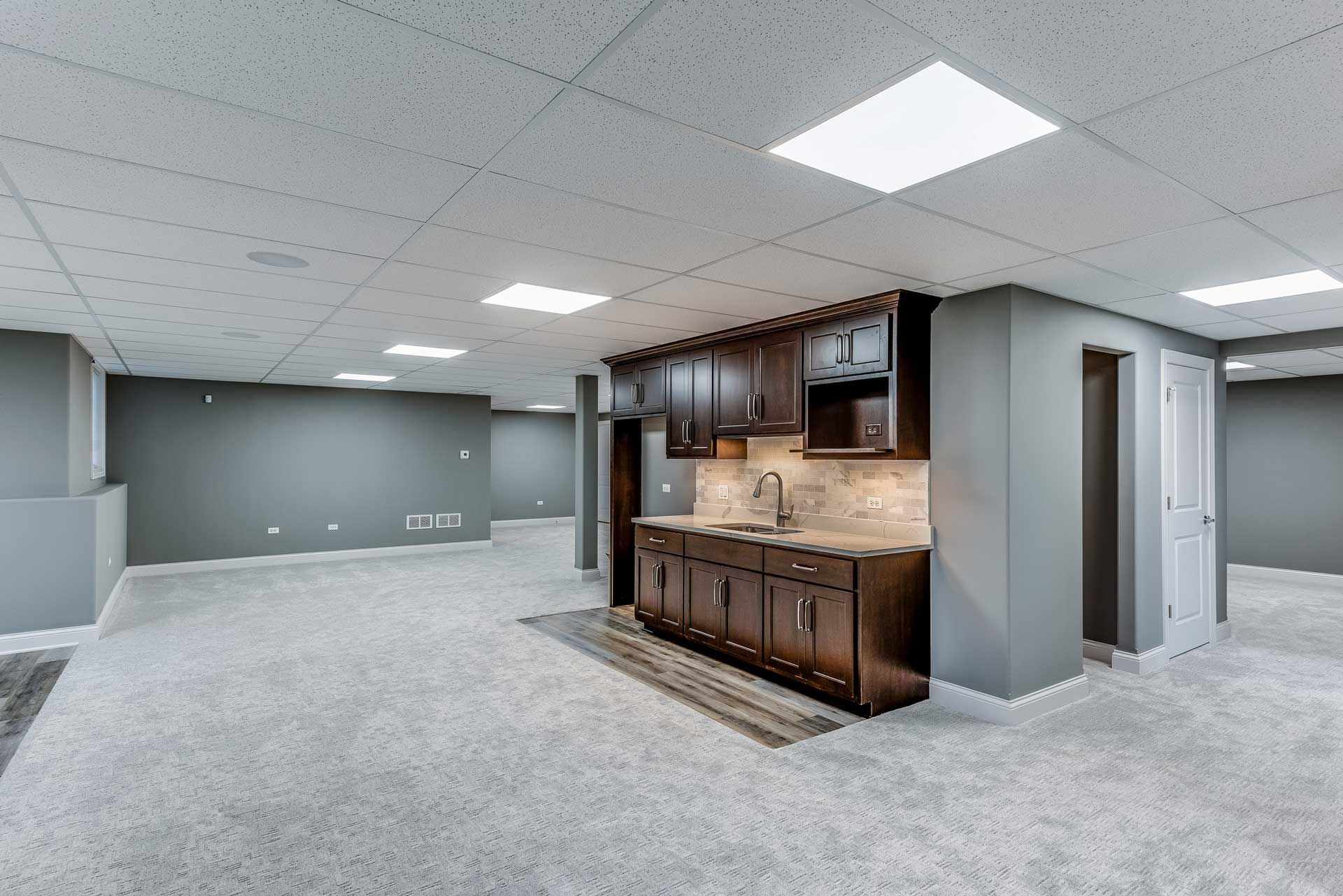 A basement with a kitchen and a bar in it.