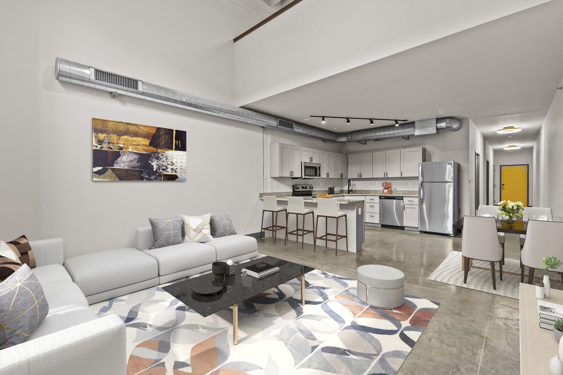 Modern open-plan living room with gray sofa, coffee table, kitchen island, and bright white decor