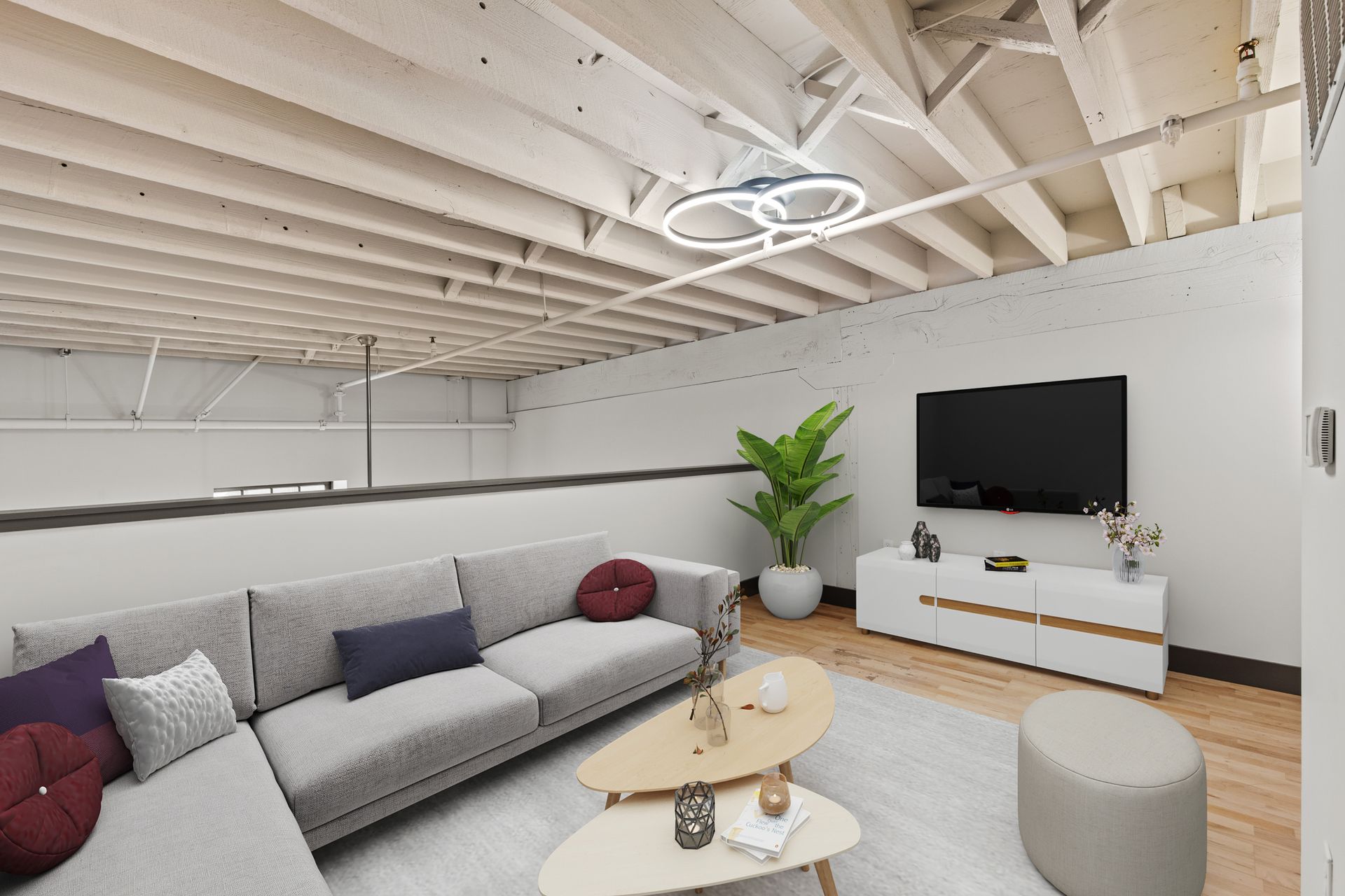 Modern living room with gray sectional sofa, white coffee table, TV, plants, and exposed beam ceiling
