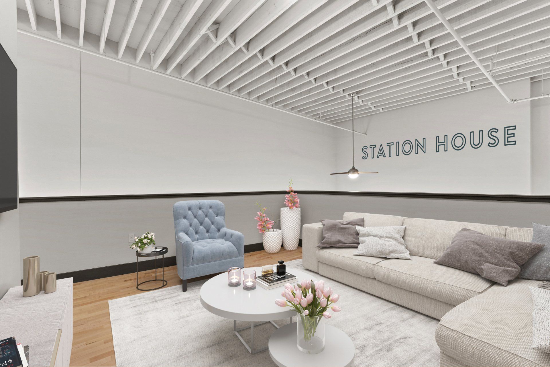 Modern lounge with cream sectional, blue chair, white coffee table, and “Station House” wall sign