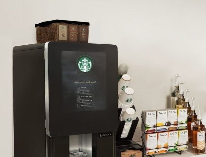 Starbucks coffee machine with stacked bags and syrups on a countertop