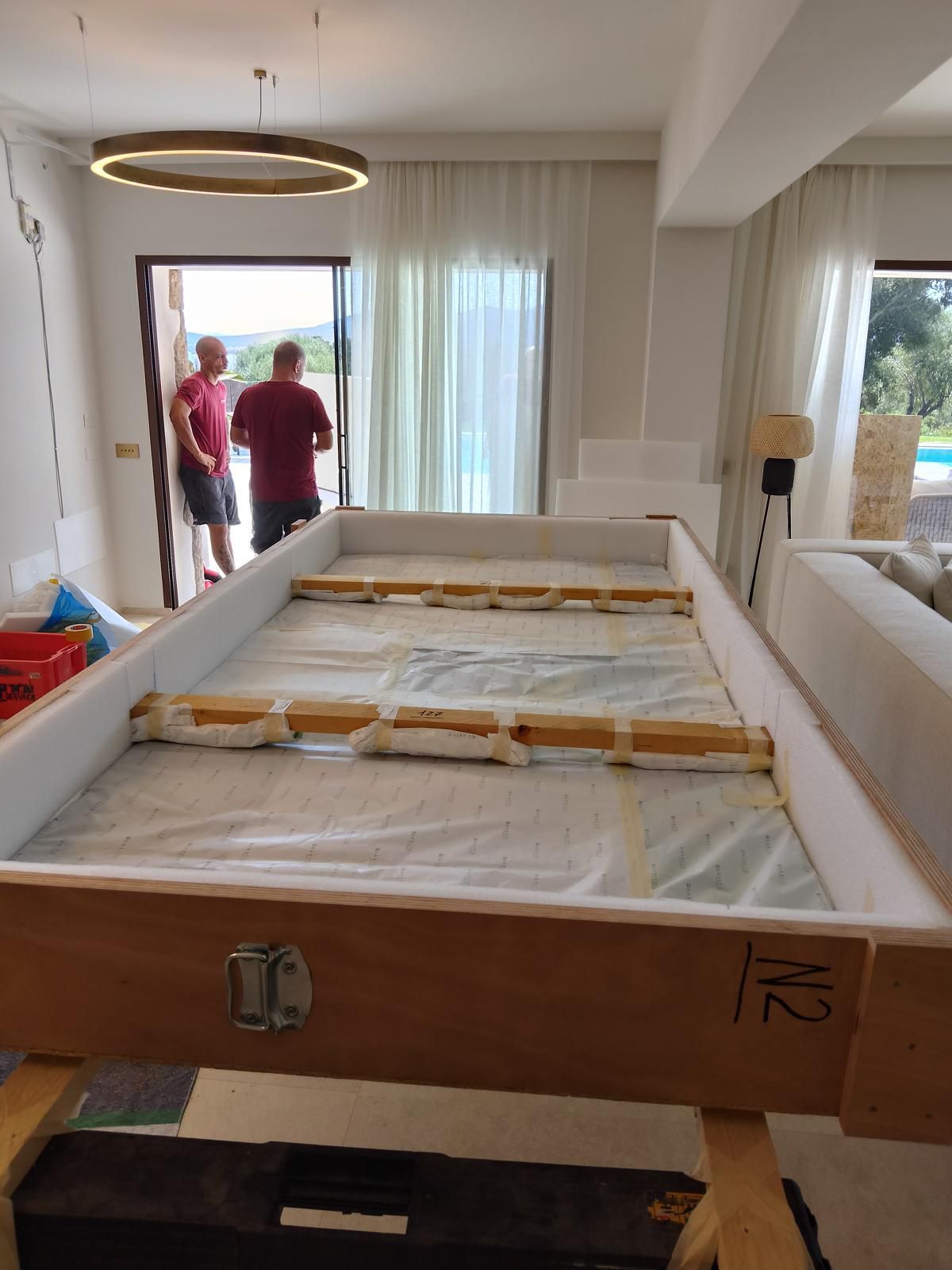 Grandi opere d'arte in un imballaggio protettivo all'interno di un edificio. Due uomini sono in piedi fuori dalla porta.