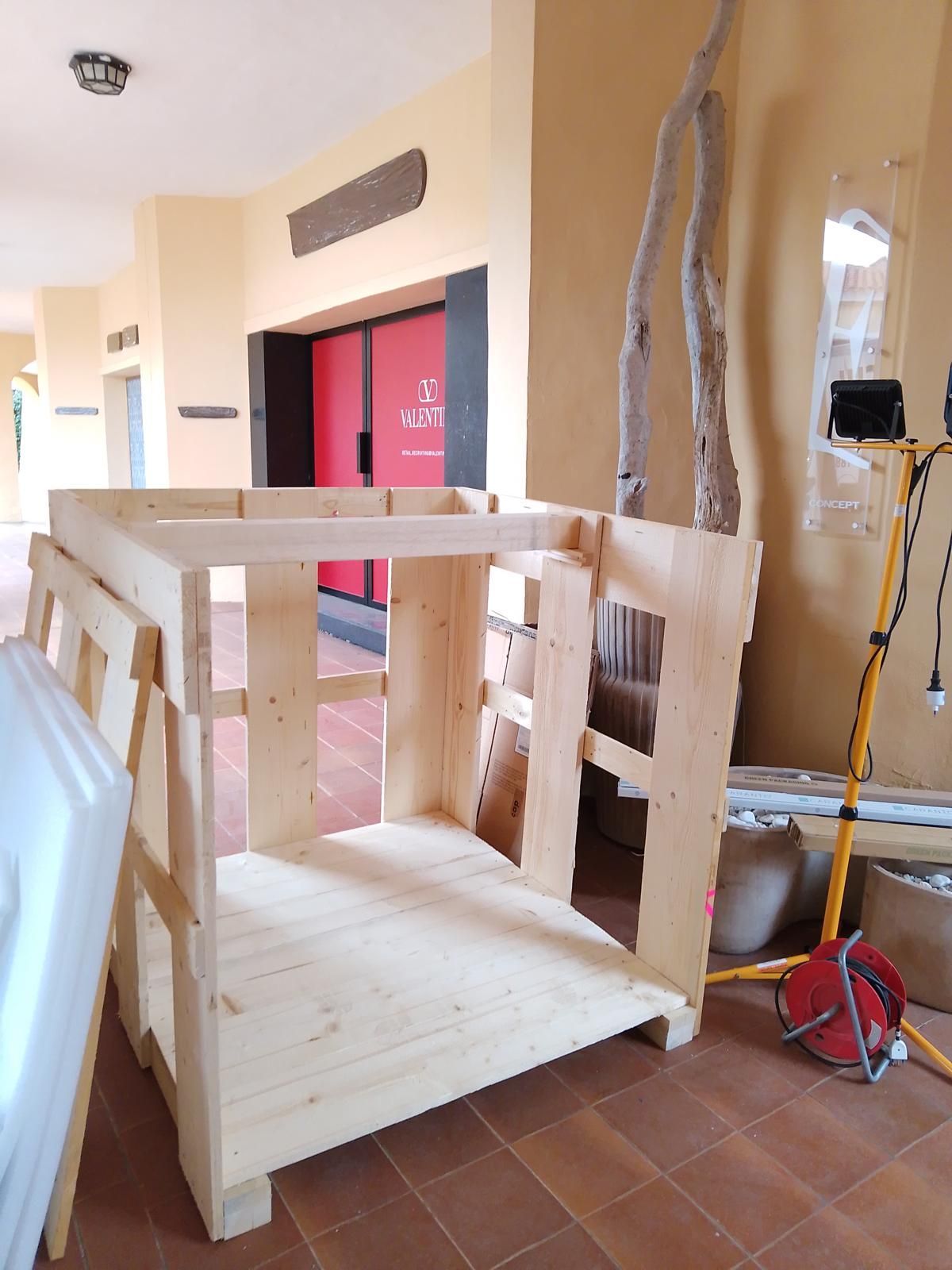 Cassa di legno in costruzione all'interno; porta rossa sullo sfondo, pareti gialle.