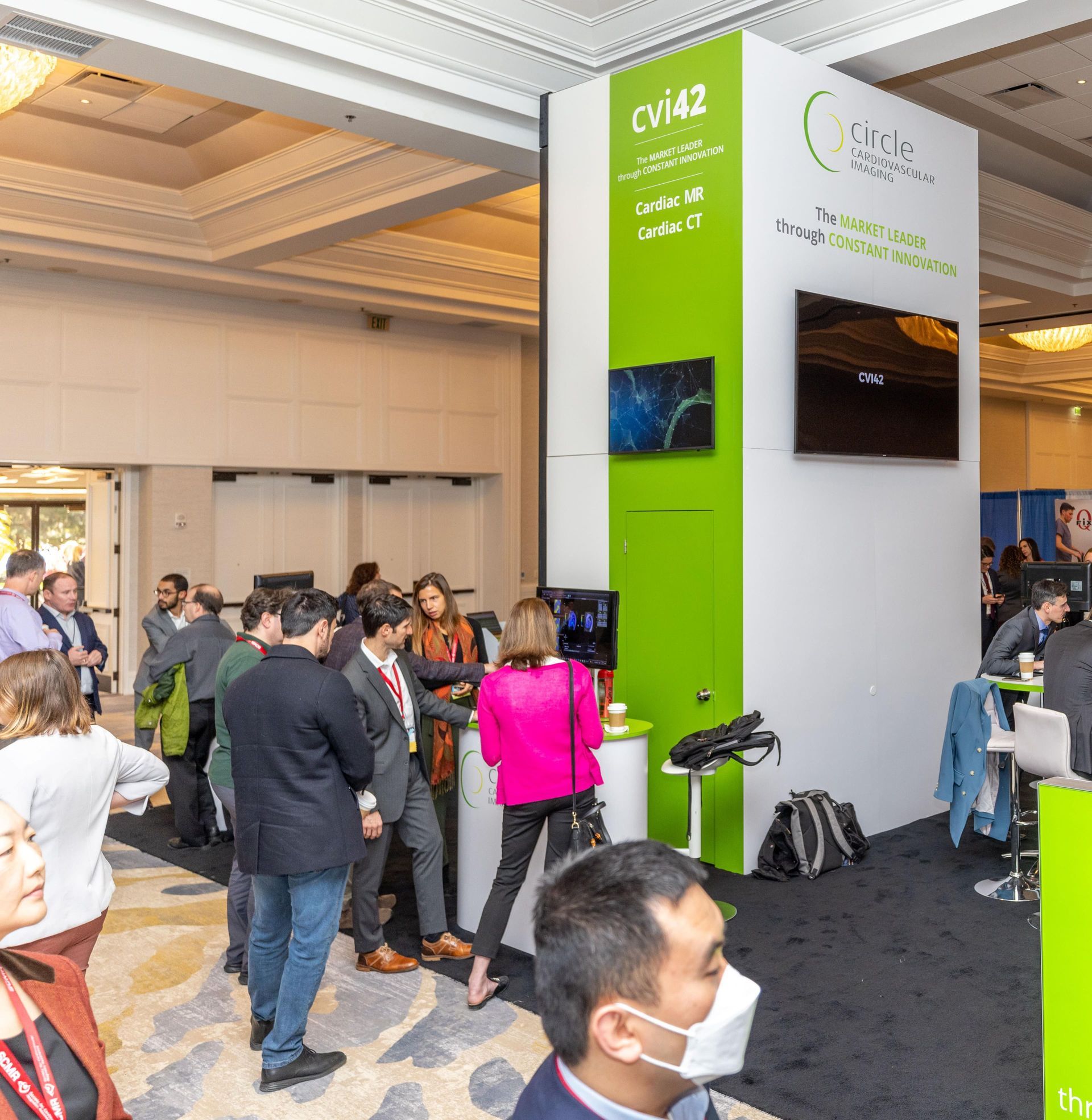 Conference attendees at a booth with a green and white sign for
