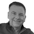 Smiling man in a dark top, head and shoulders portrait.