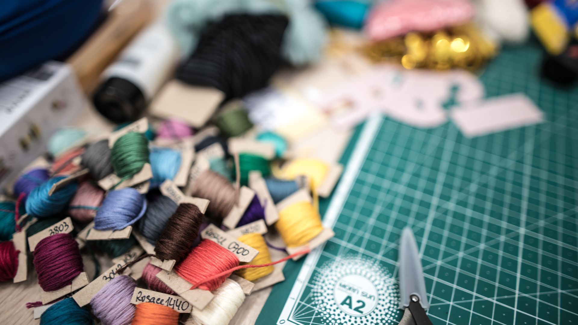 A pile of spools of thread and scissors on a cutting board.