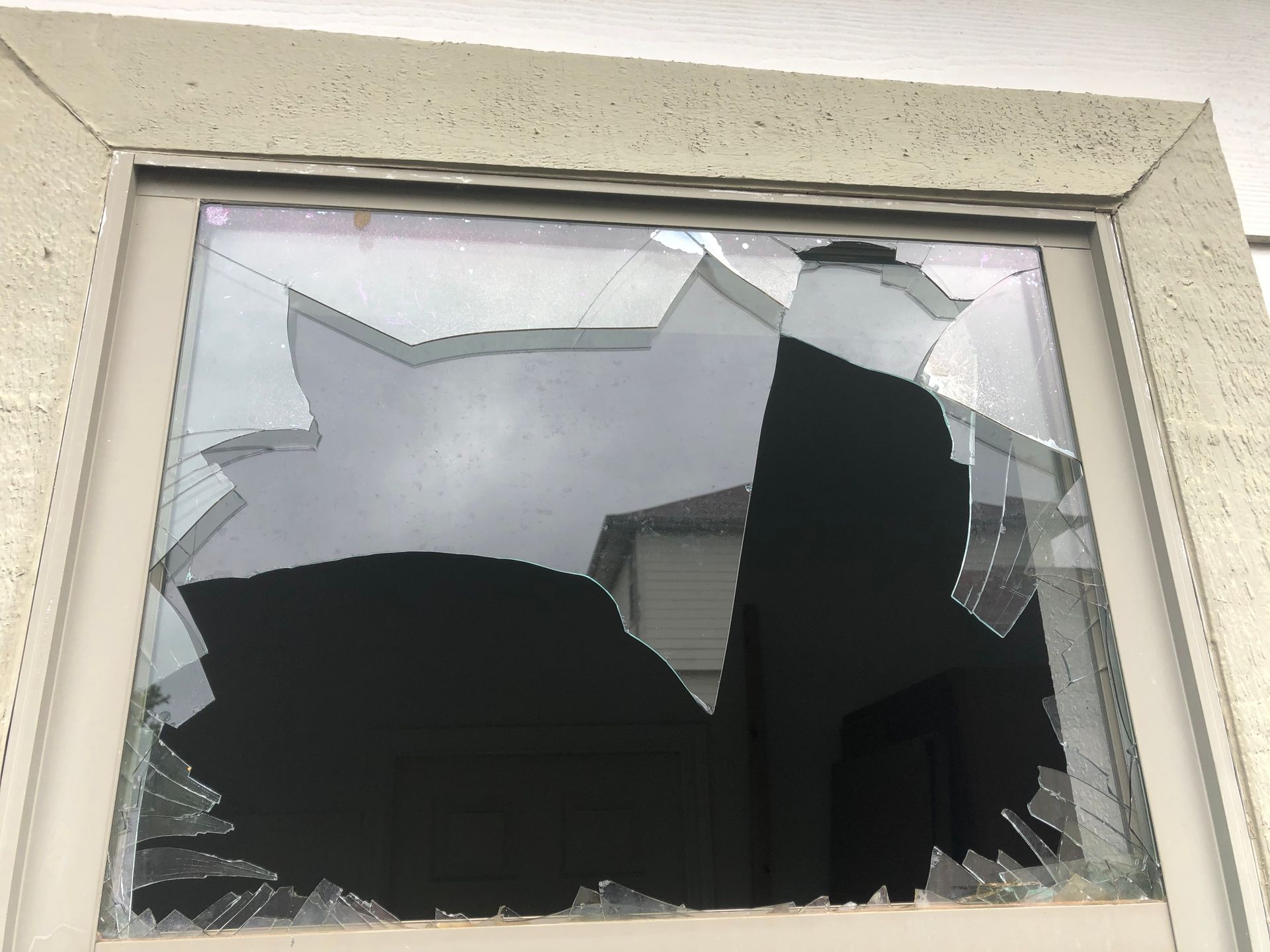 A broken window with a reflection of a building in it