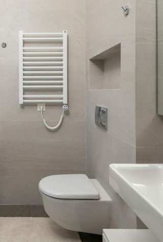 A bathroom with a toilet , sink , and towel rack.