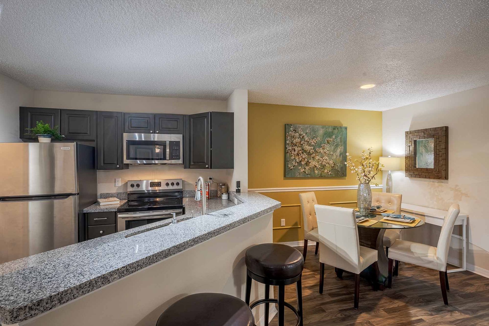 Kitchen and dining area with granite countertop, stainless steel appliances, and round dining table. Discover thoughtfully designed Apts in Clearwater, FL with a personal tour.