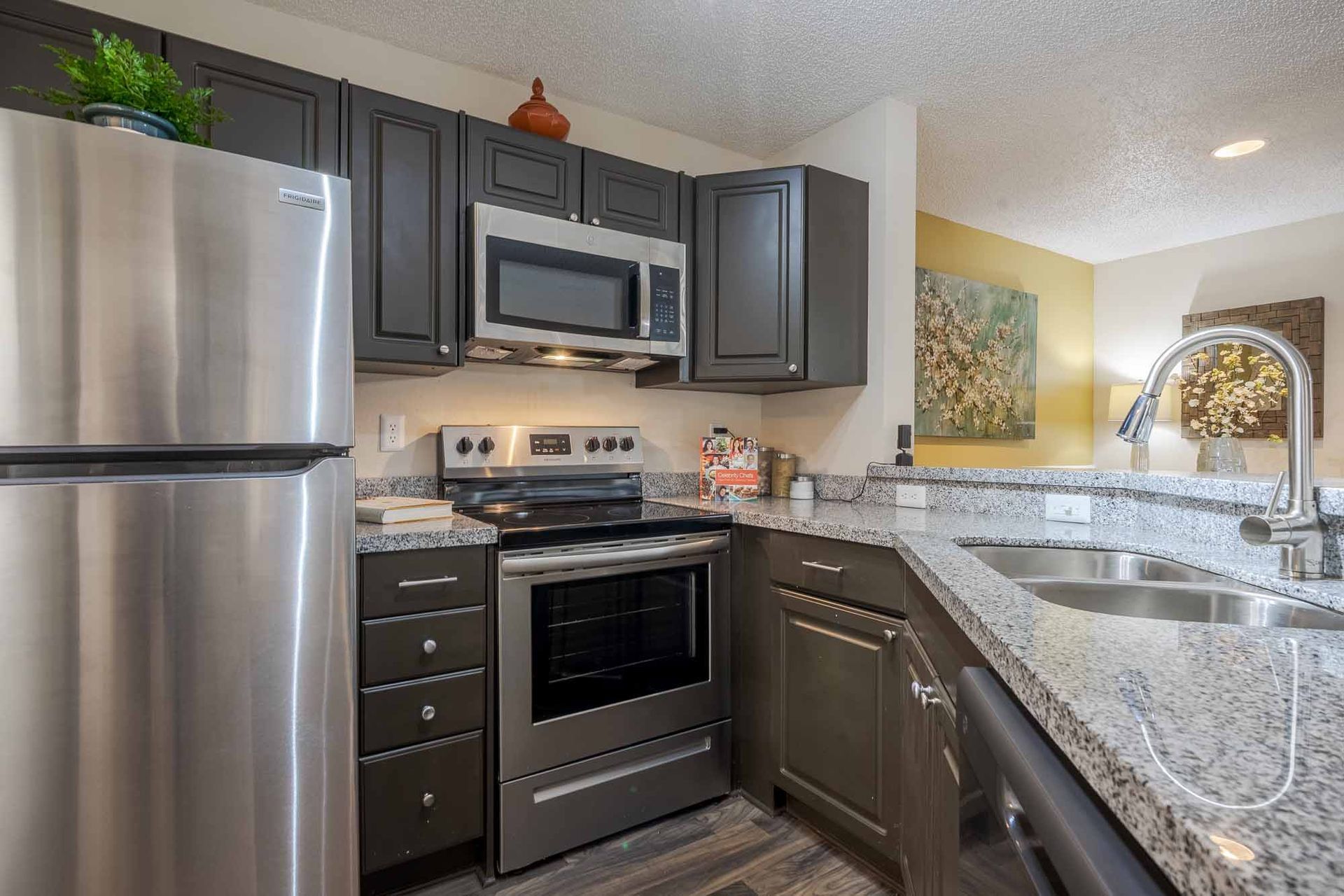 Stainless steel kitchen appliances, dark cabinets, granite countertop, sink, corner view. Come see why our Clearwater, FL apartments for rent feel like home—book your tour.