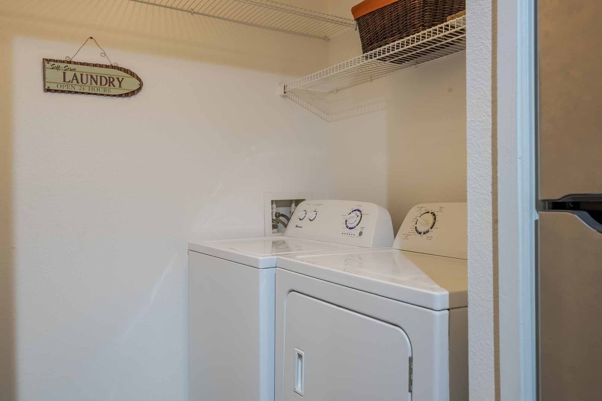 Laundry room with a washer and dryer, shelf, and a laundry sign. Walk through our beautifully finished Apartments in Clearwater, FL soon.