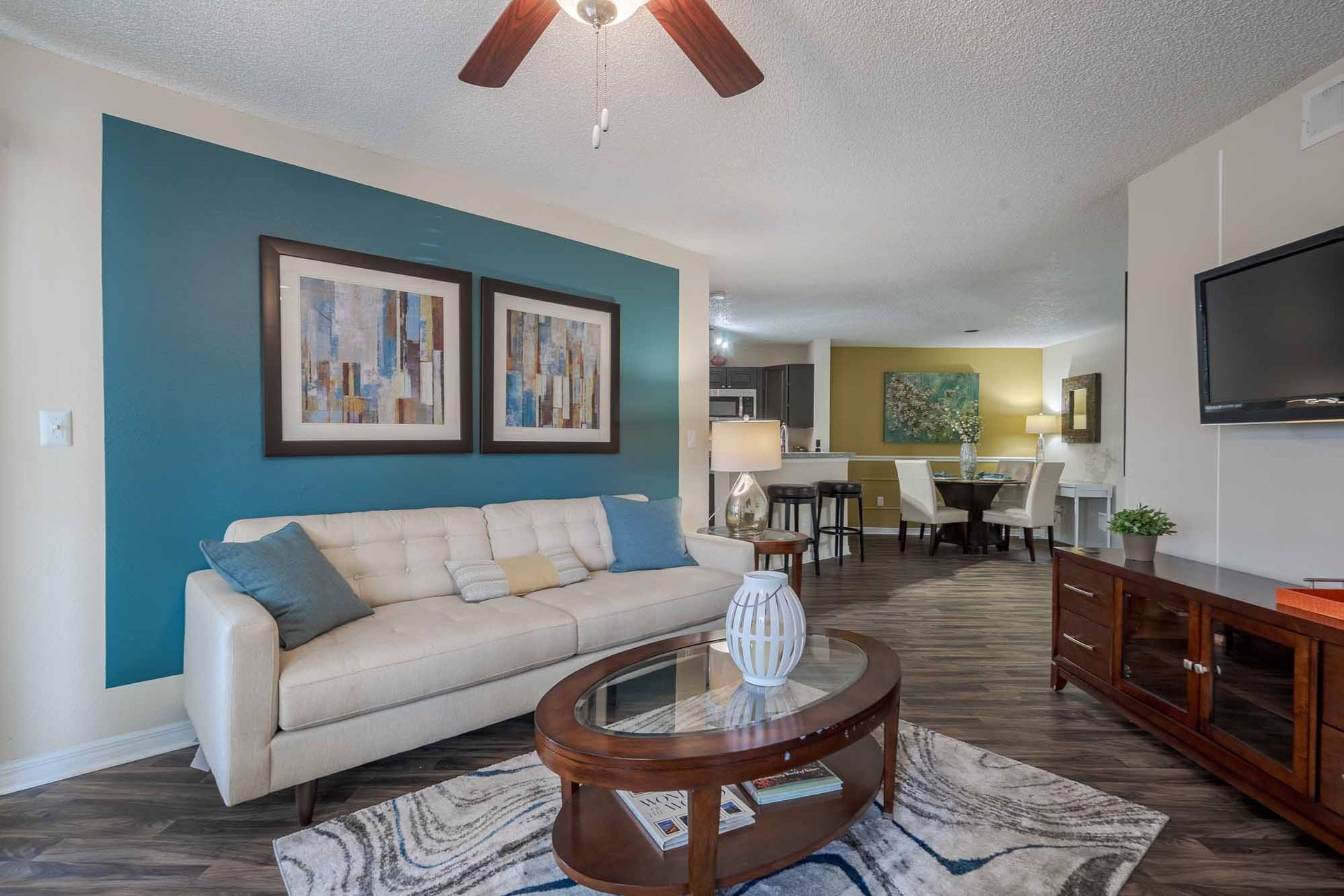 Living room with teal accent wall, white sofa, coffee table, and television. Take the next step and tour our modern Clearwater, FL apartments.