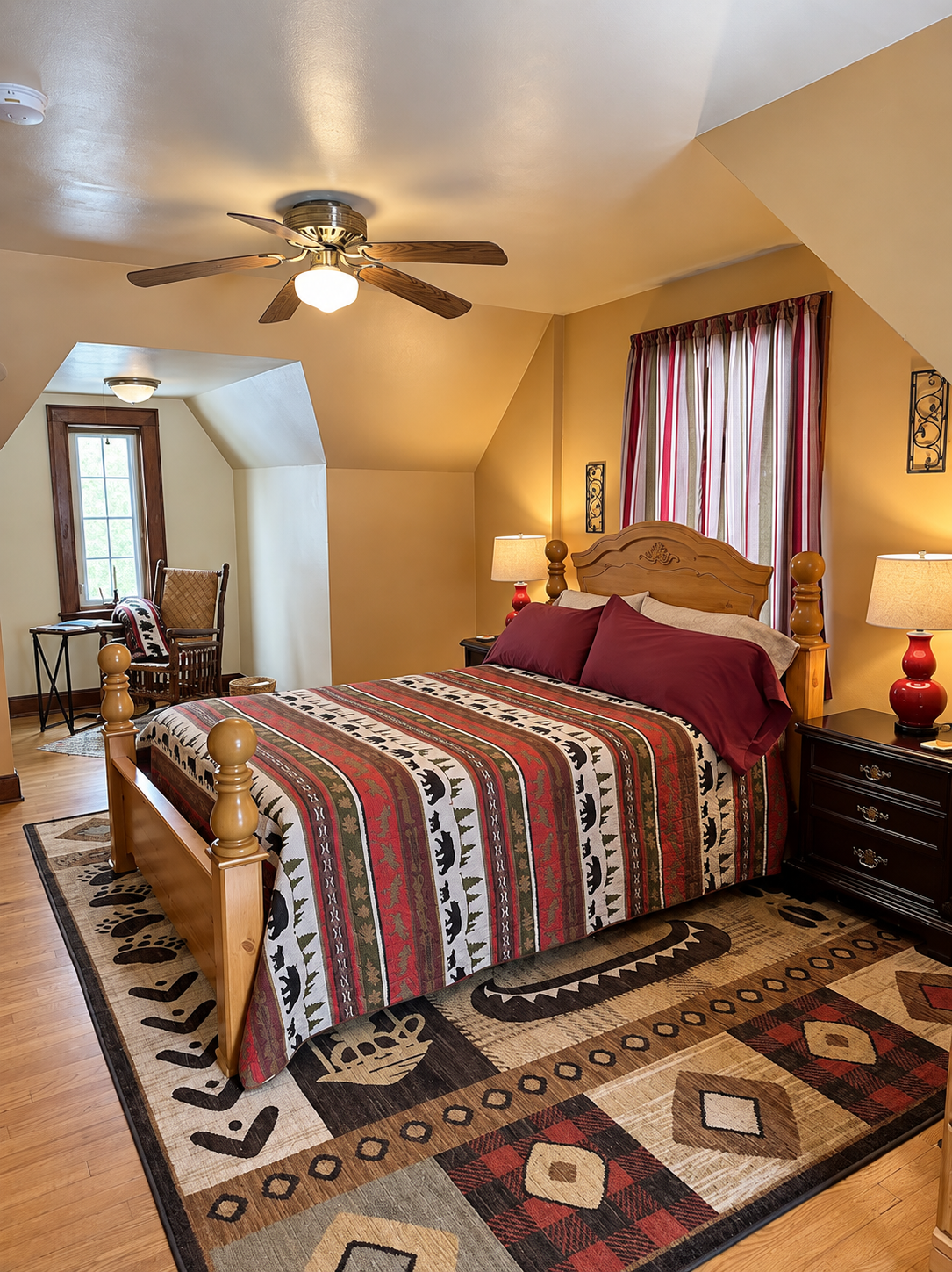 Cozy upstairs bedroom at Red Fox Townhouse with a wooden bed frame, ceiling fan and warm bedside lighting.