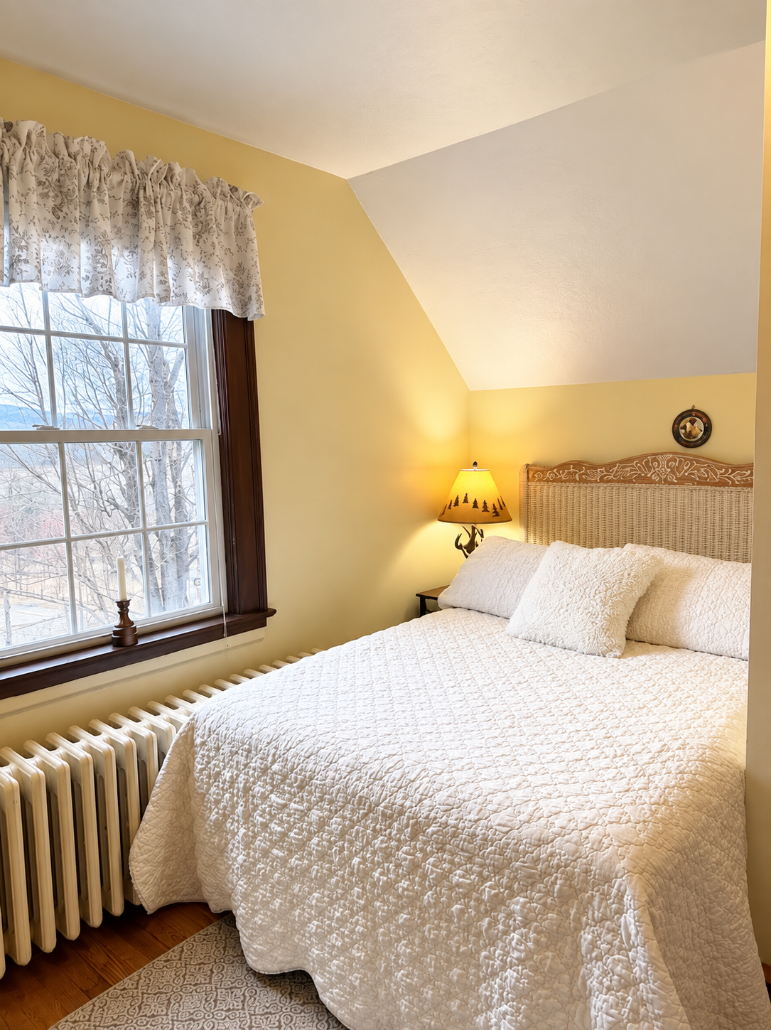 Bright bedroom in the Red Fox Townhouse with a window, soft curtains, warm lighting and windham mountain club views.