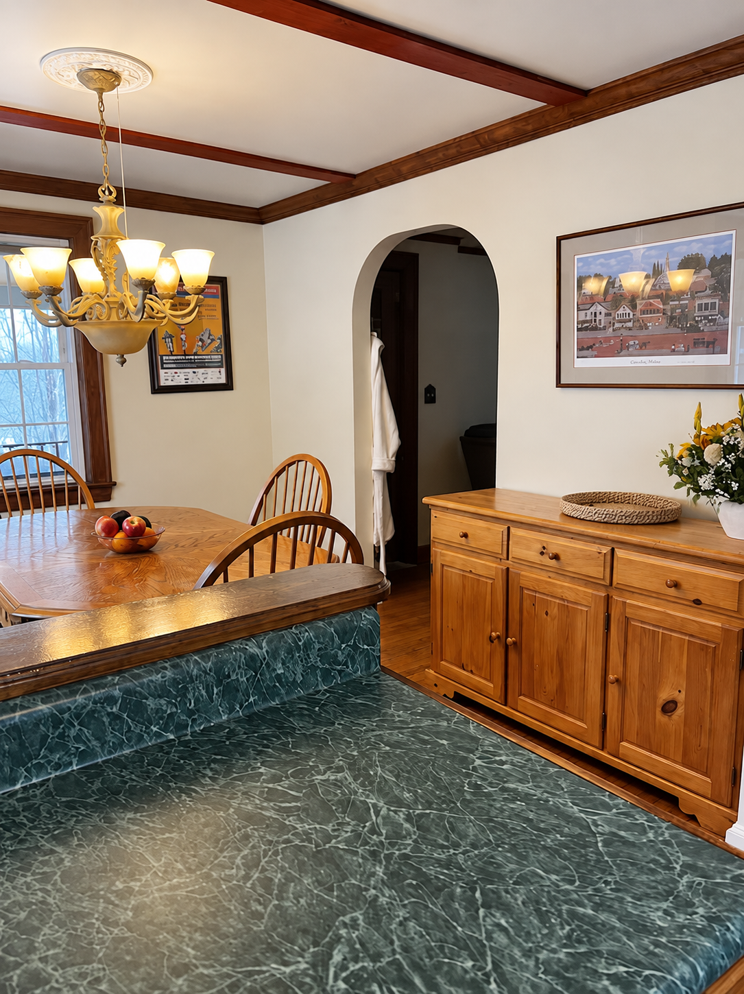 Red Fox Townhouse dining area featuring exposed wooden ceiling beams, a chandelier and warm Catskills-inspired decor.