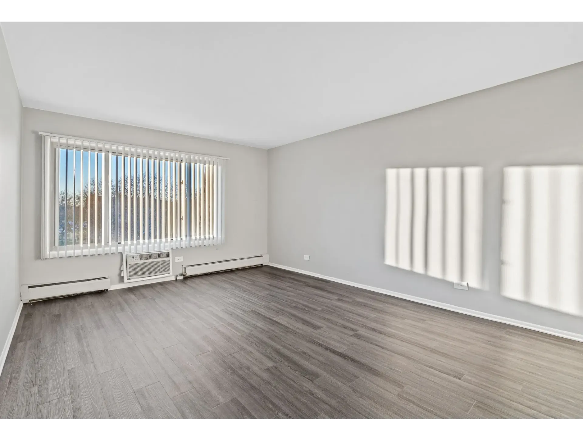 Spacious living room with large window and blinds