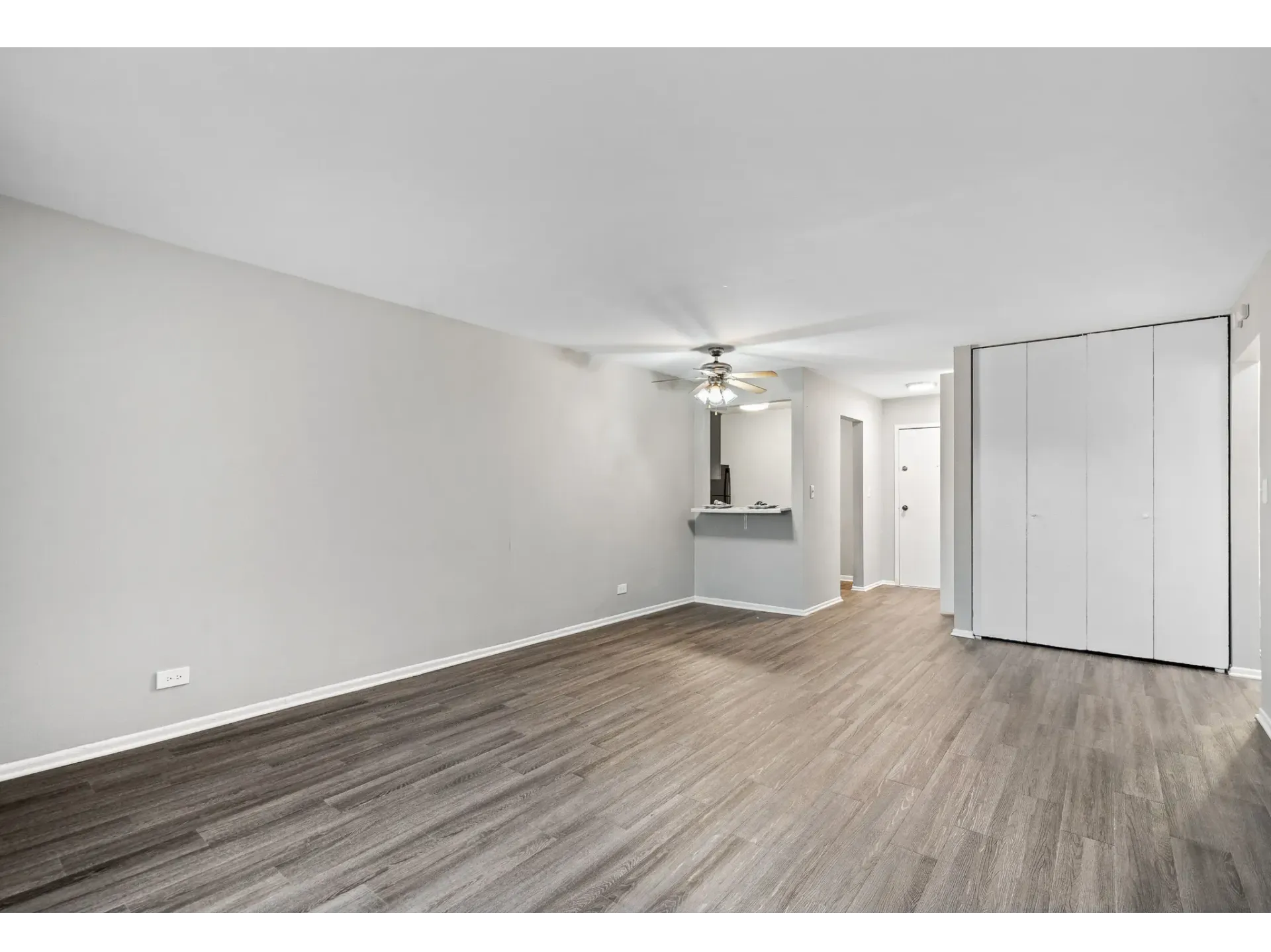 Spacious apartment interior with gray walls and brown flooring.