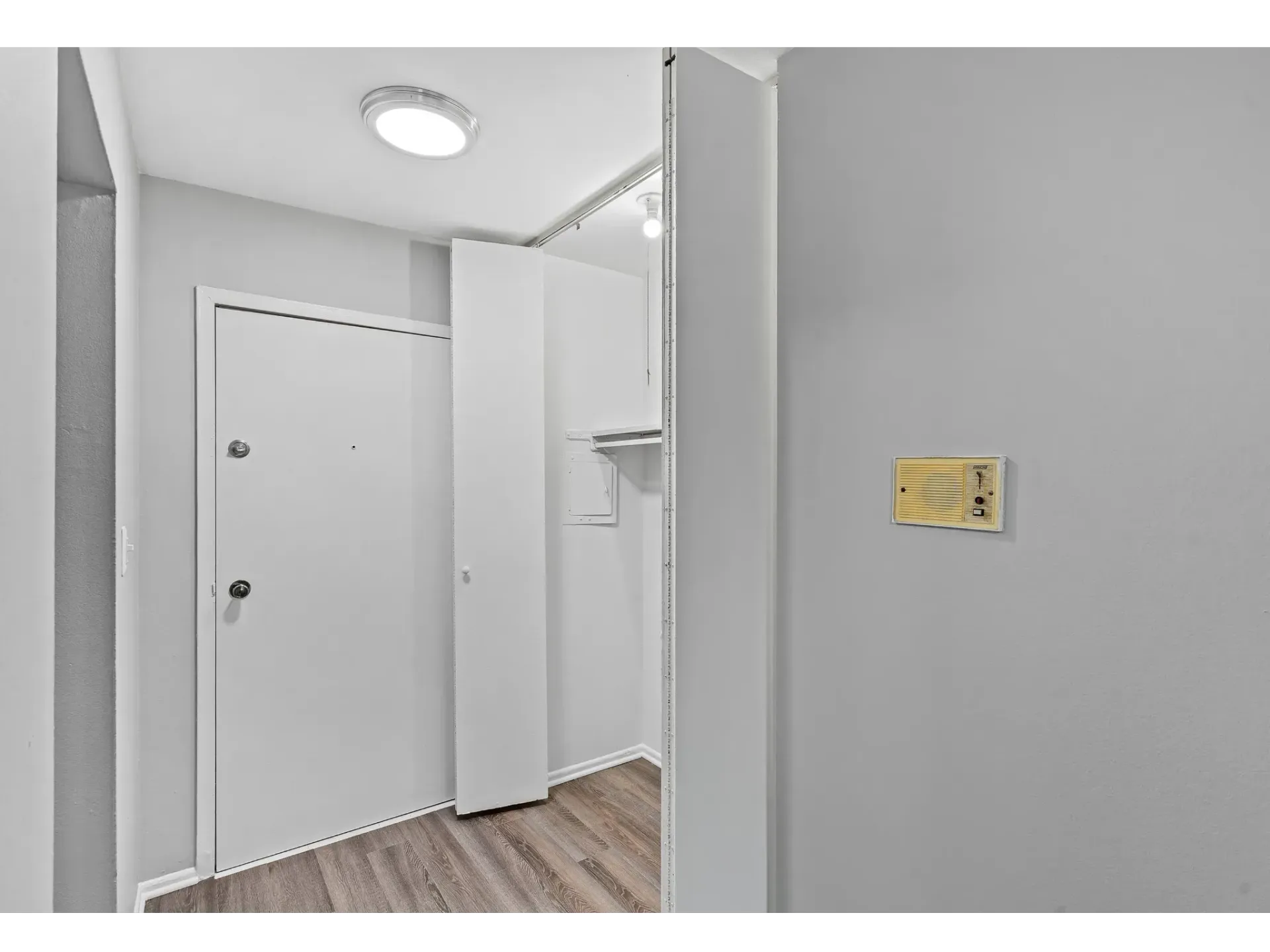 Entrance hall of an apartment unit with a white door and wooden floor