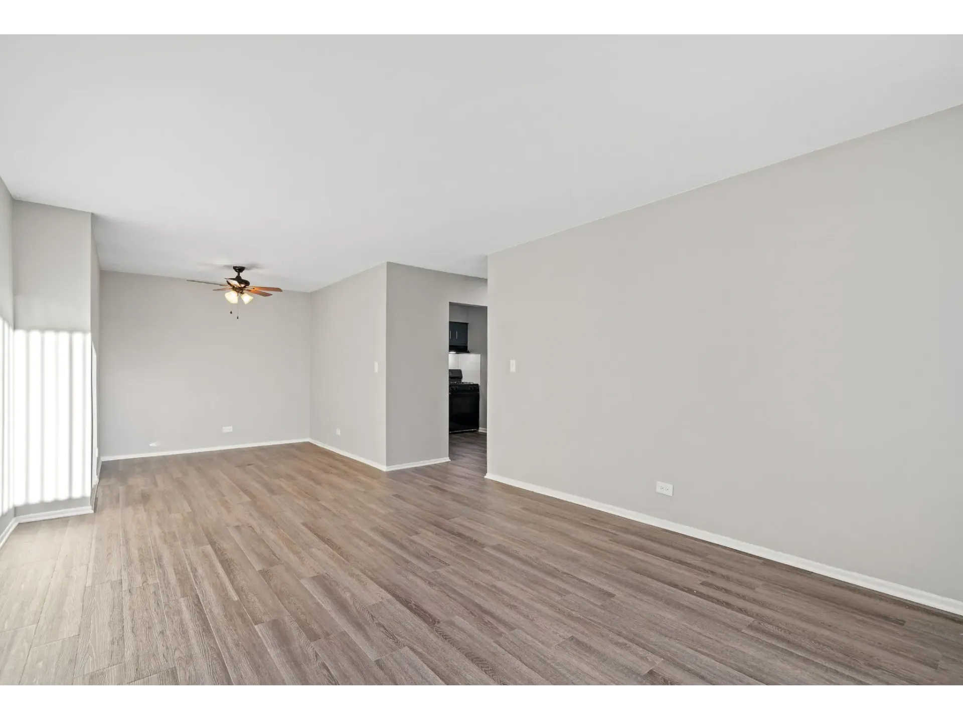 Spacious living area with light-colored walls and wooden floor.