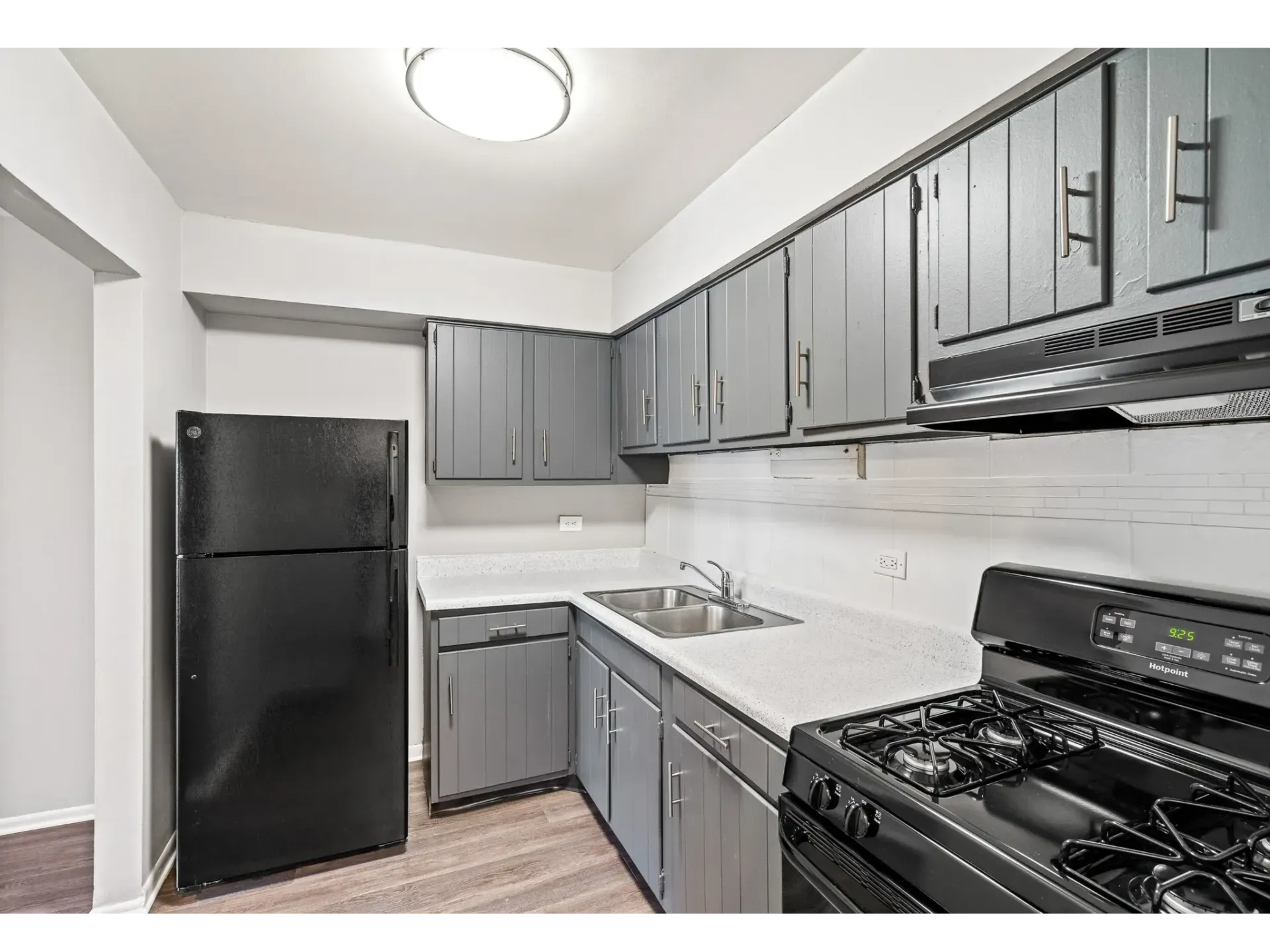 Kitchen with black refrigerator, gas stove, and gray cabinets
