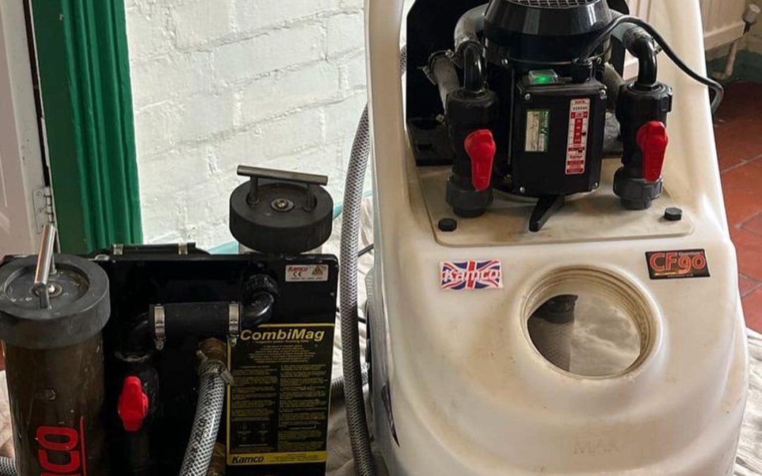 Floor cleaning machine and attached parts. Black and white machine with red valves, against a white wall.