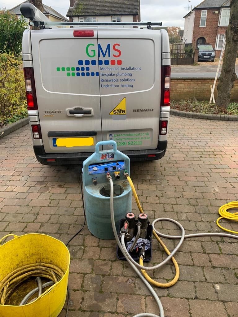 A GMS service van parked on a paved driveway with cleaning equipment, including a blue unit and yellow hoses, in the front.