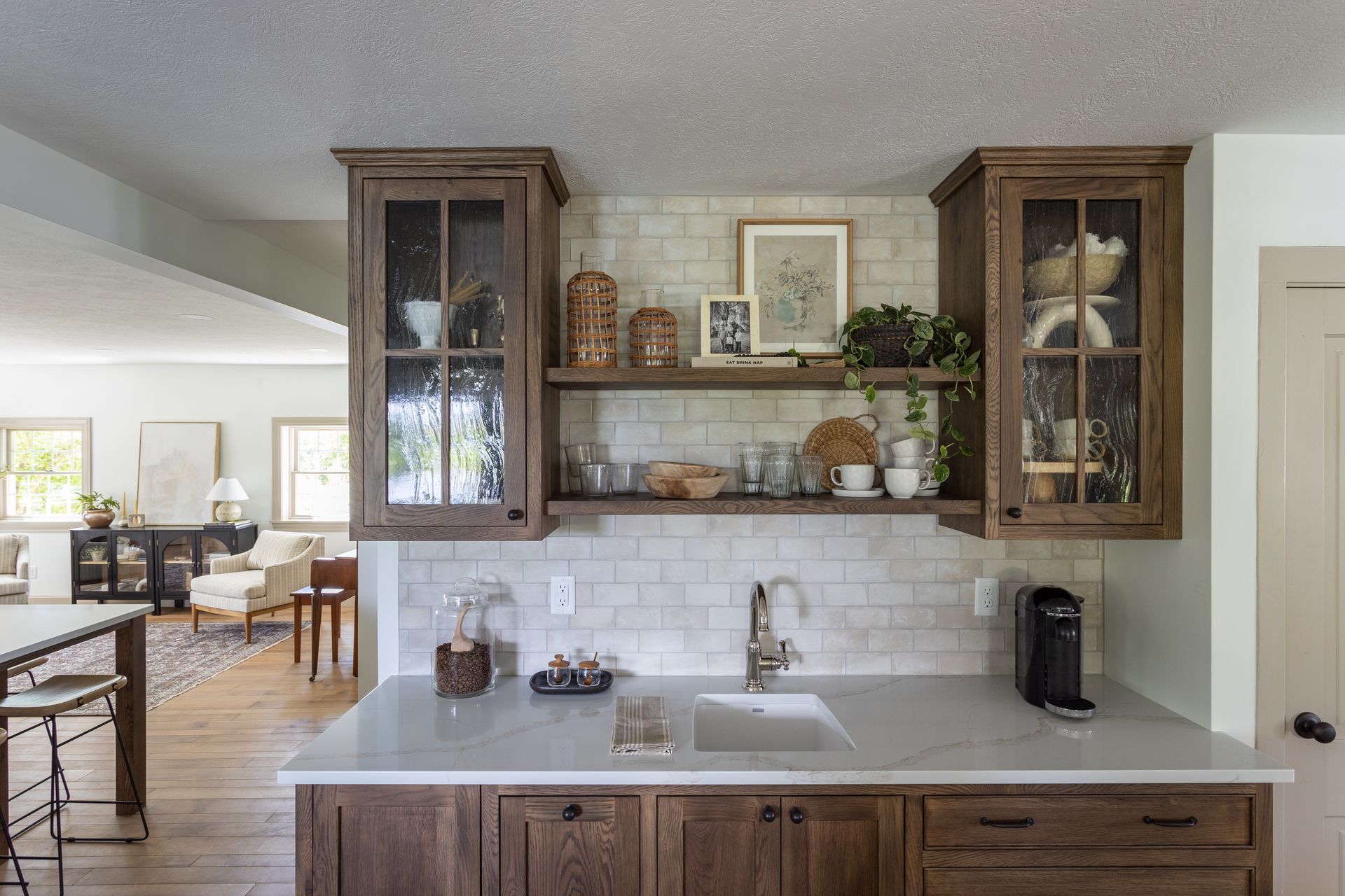 Kitchen with wooden cabinets, marble countertop, sink, and shelves with décor.