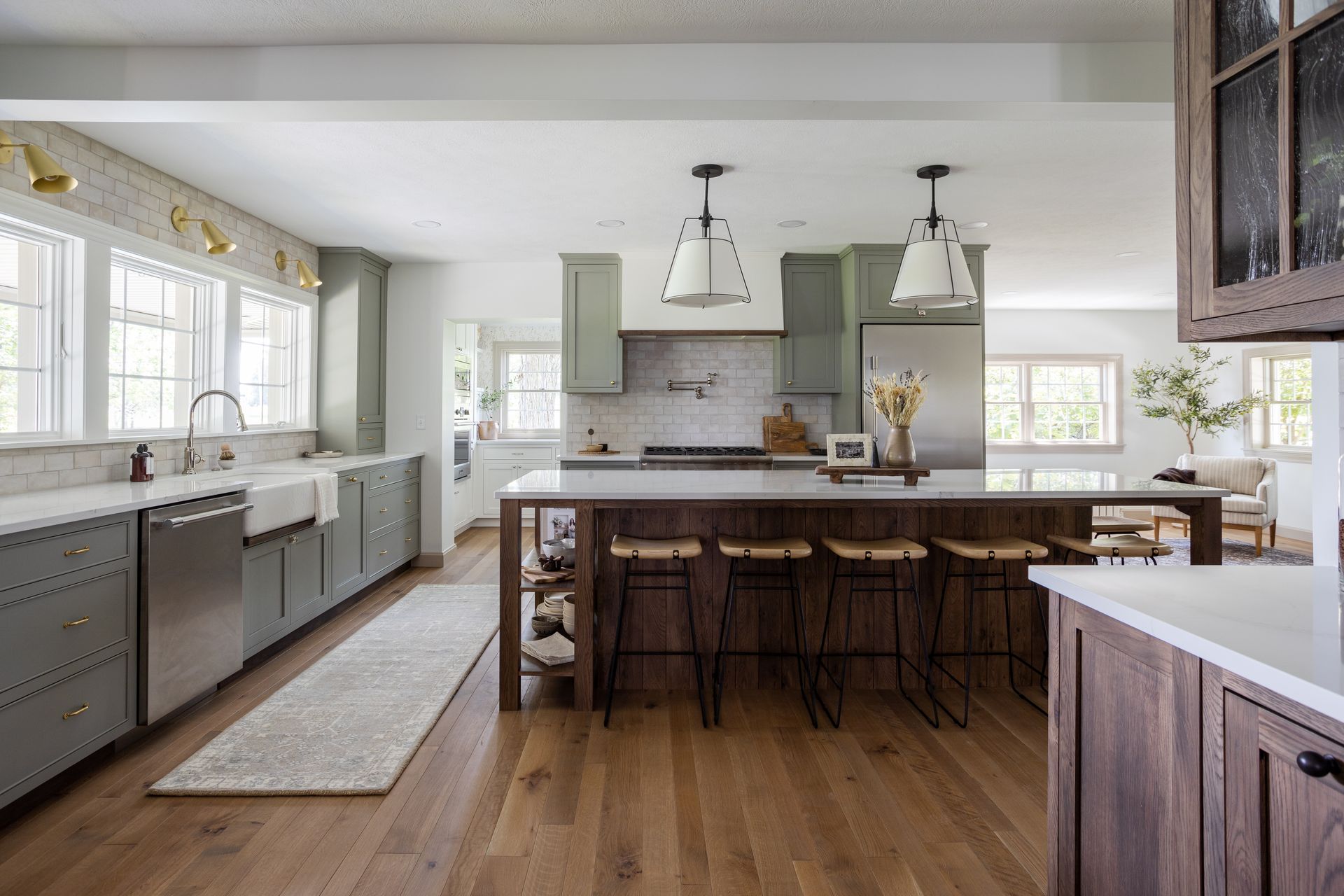 Spacious kitchen with gray cabinets, white countertops, a large island, and wood flooring.