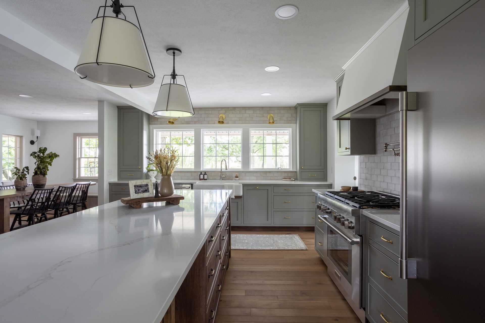 Modern kitchen with sage green cabinets, white countertops, and wood floors.