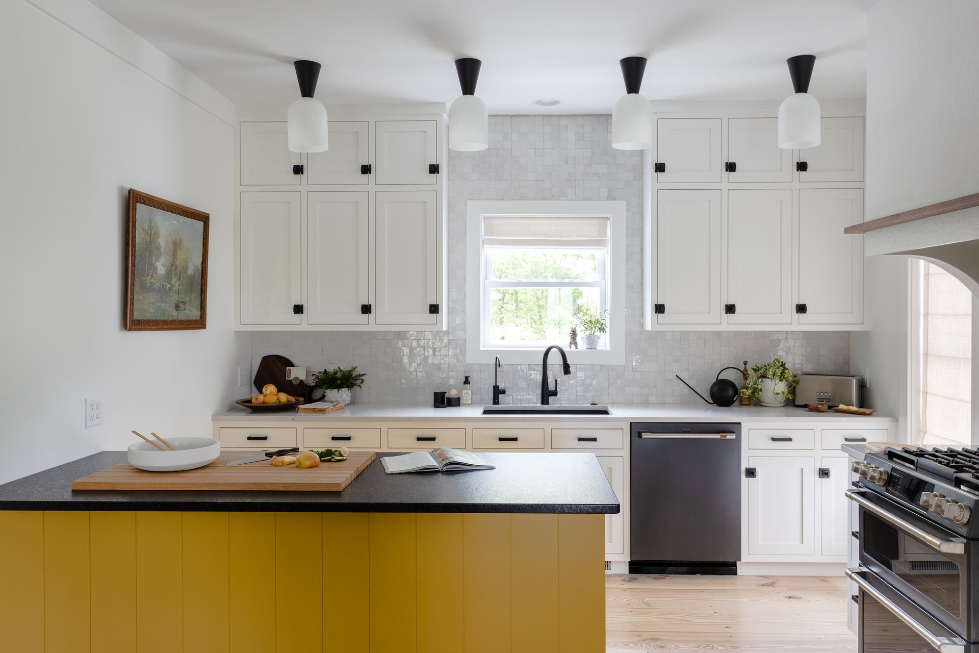 Yellow and white kitchen with island, black accents, and four hanging lights.