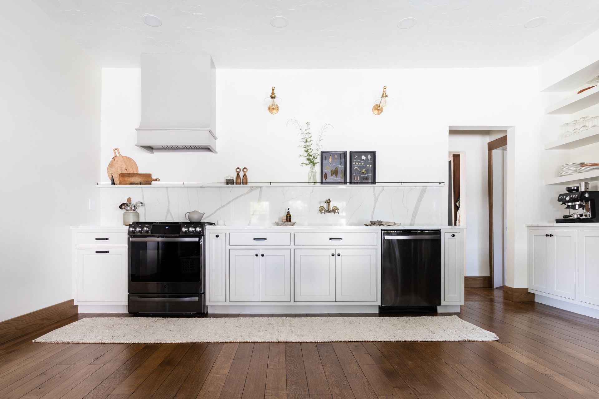 White kitchen with dark appliances, marble backsplash, and wooden floors.