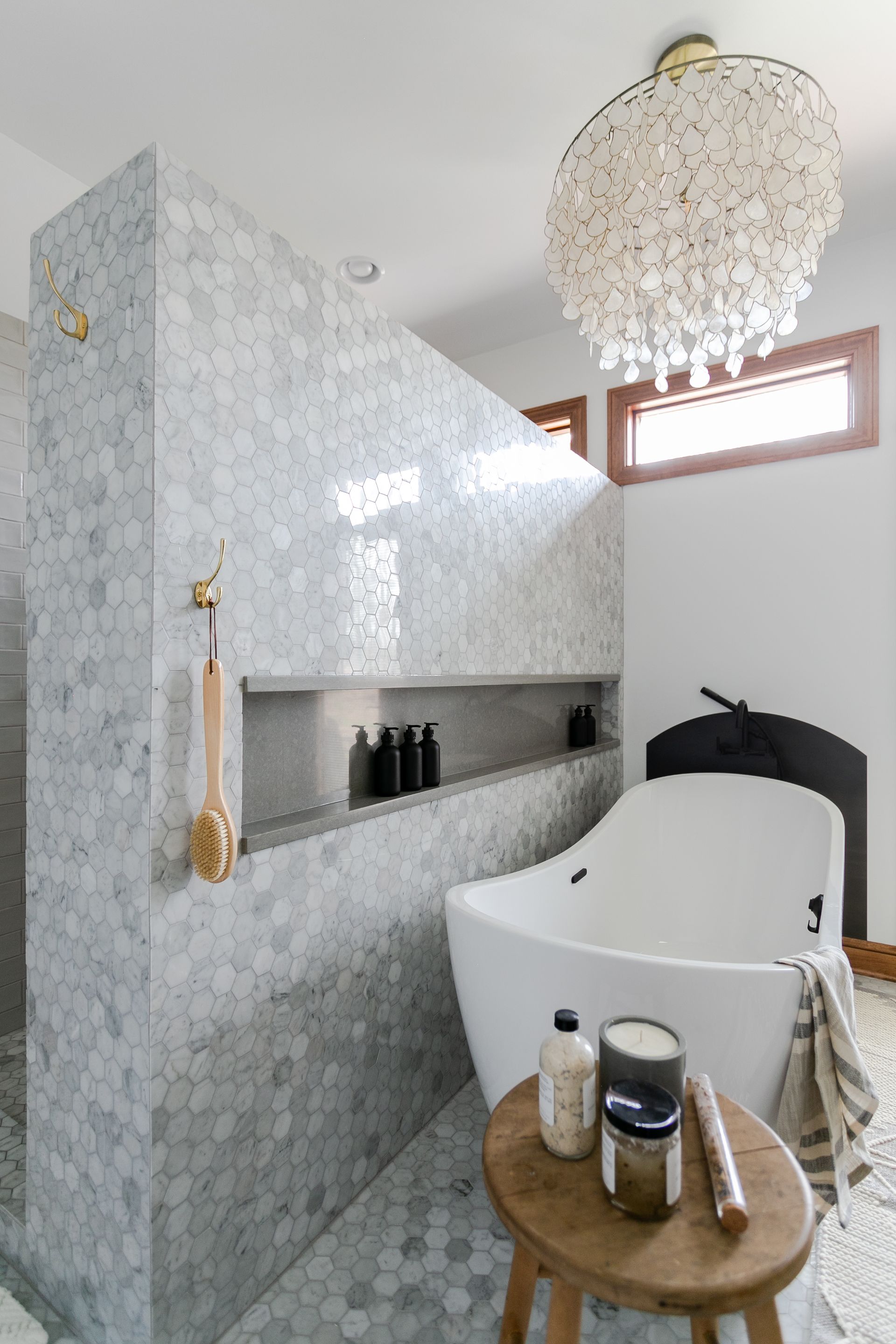 Bathroom with a marble tile shower, freestanding tub, and a decorative light fixture.