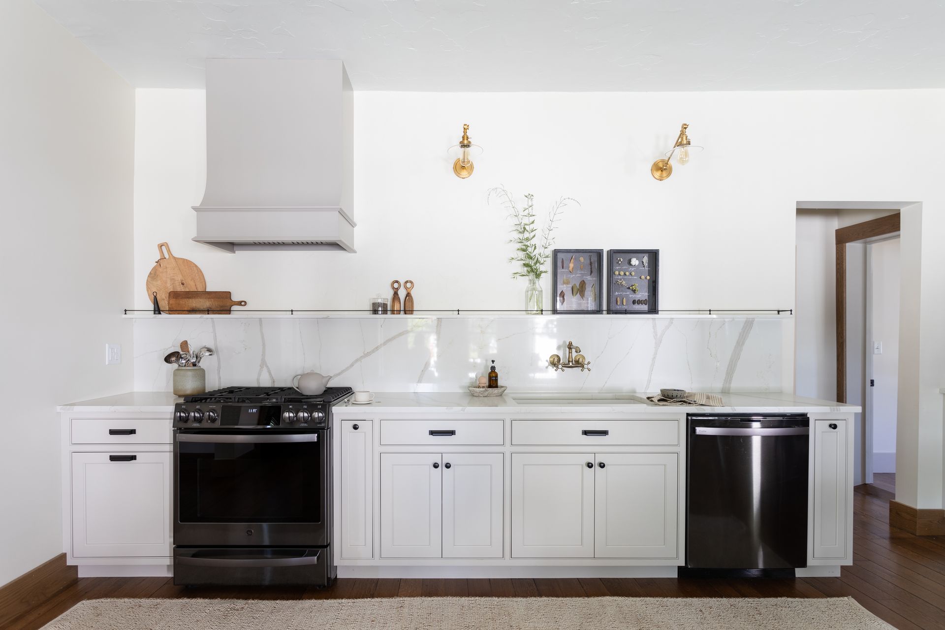 White kitchen with stove, cabinets, and dishwasher; marble backsplash and wall-mounted sconces.