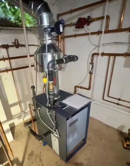 Basement furnace with metal ductwork and copper pipes in a utility room