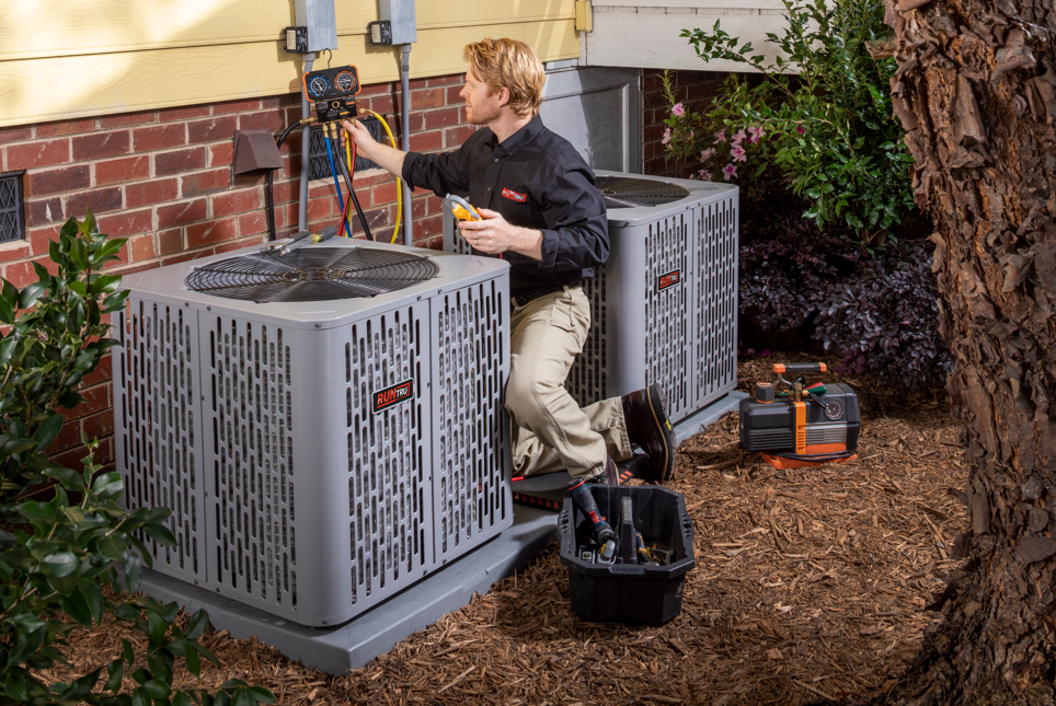 A technician with a screwdriver is repairing an air conditioner.