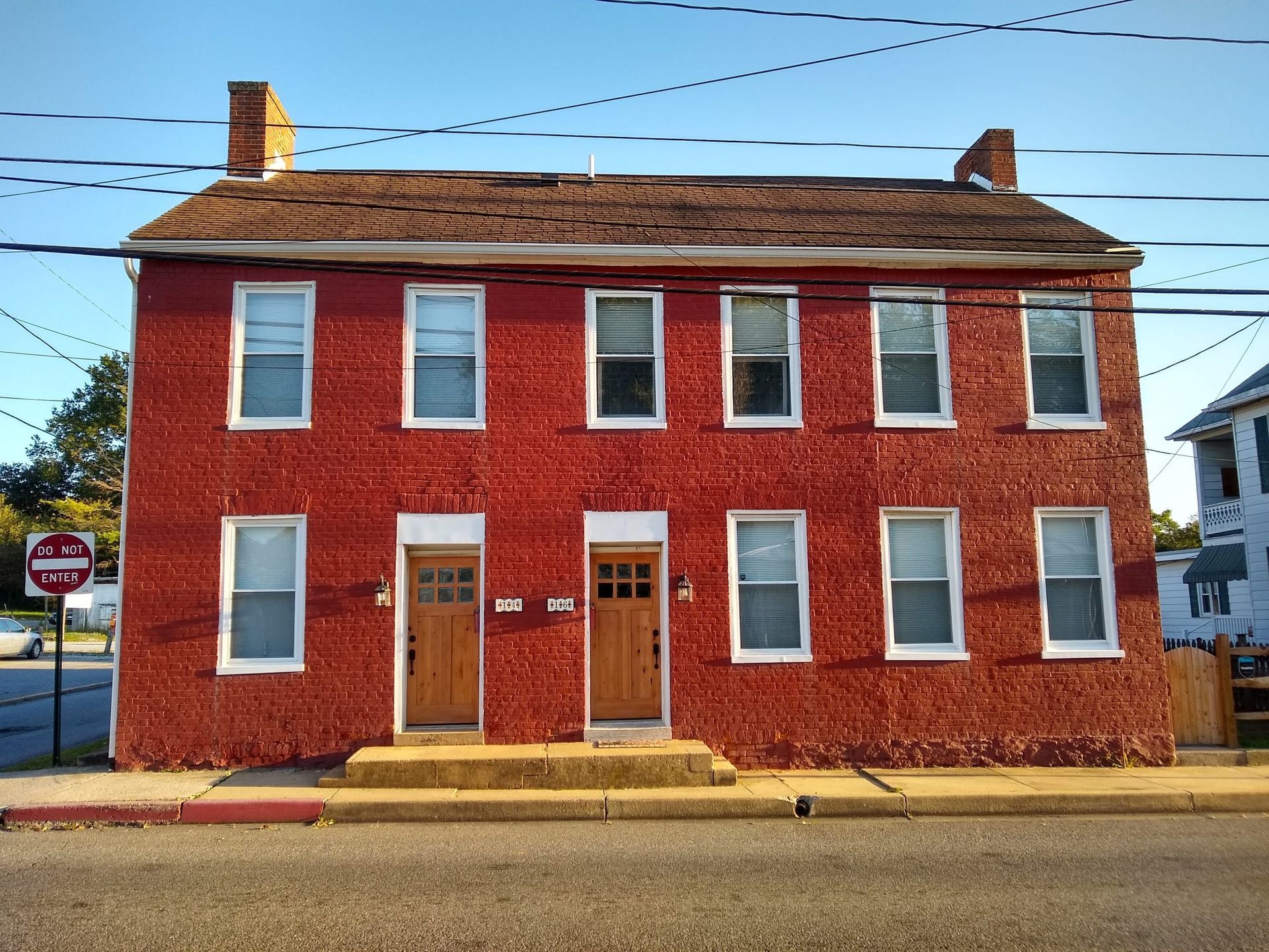 Red brick two-story building with white-trimmed windows and a central entrance on a street corner