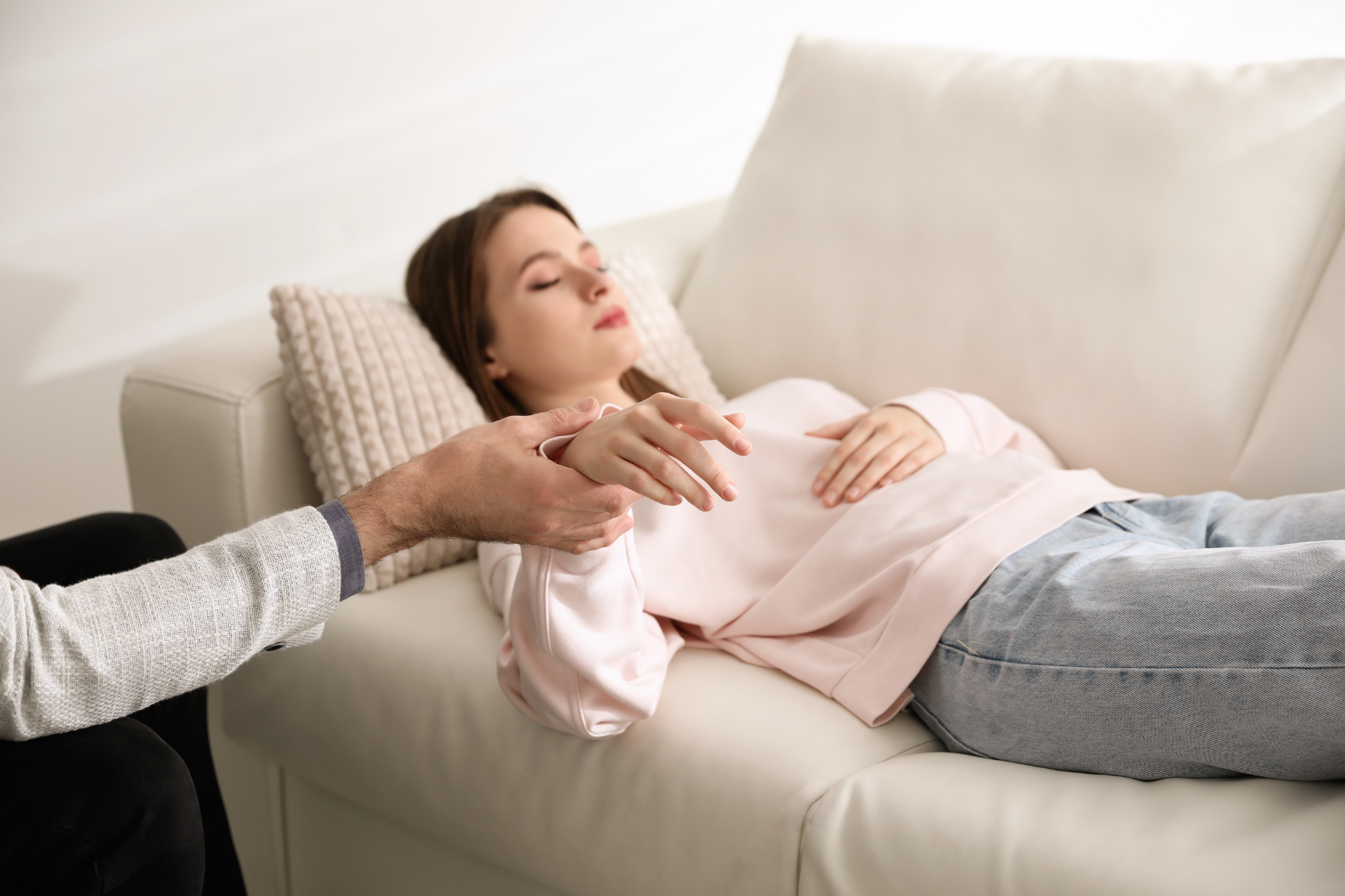 A woman is laying on a couch with her eyes closed.