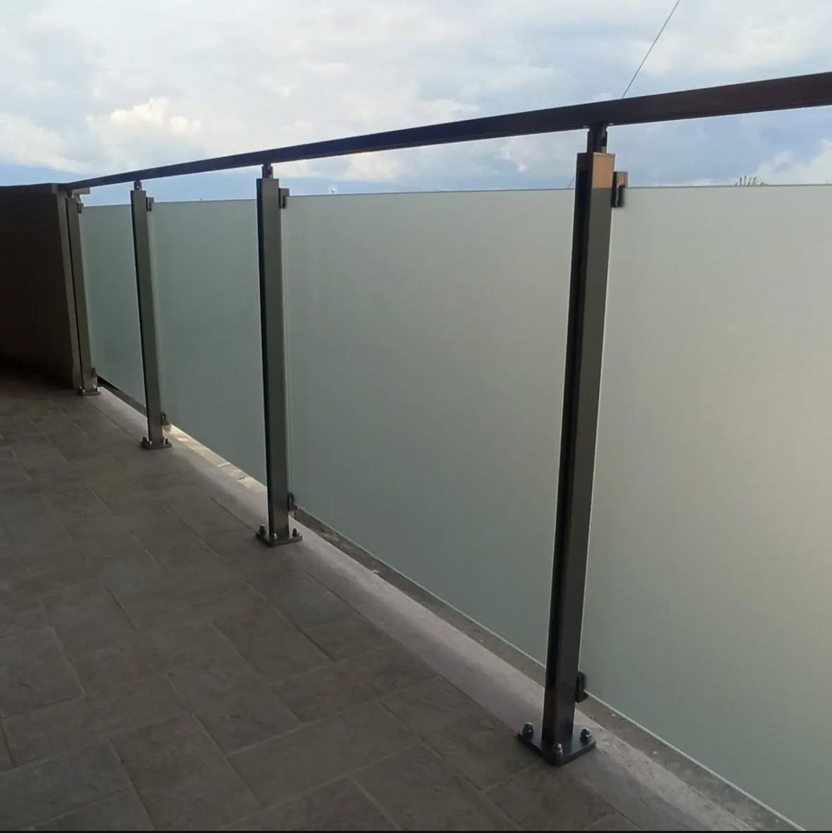 Balcone con pannelli in vetro smerigliato e ringhiera in metallo.