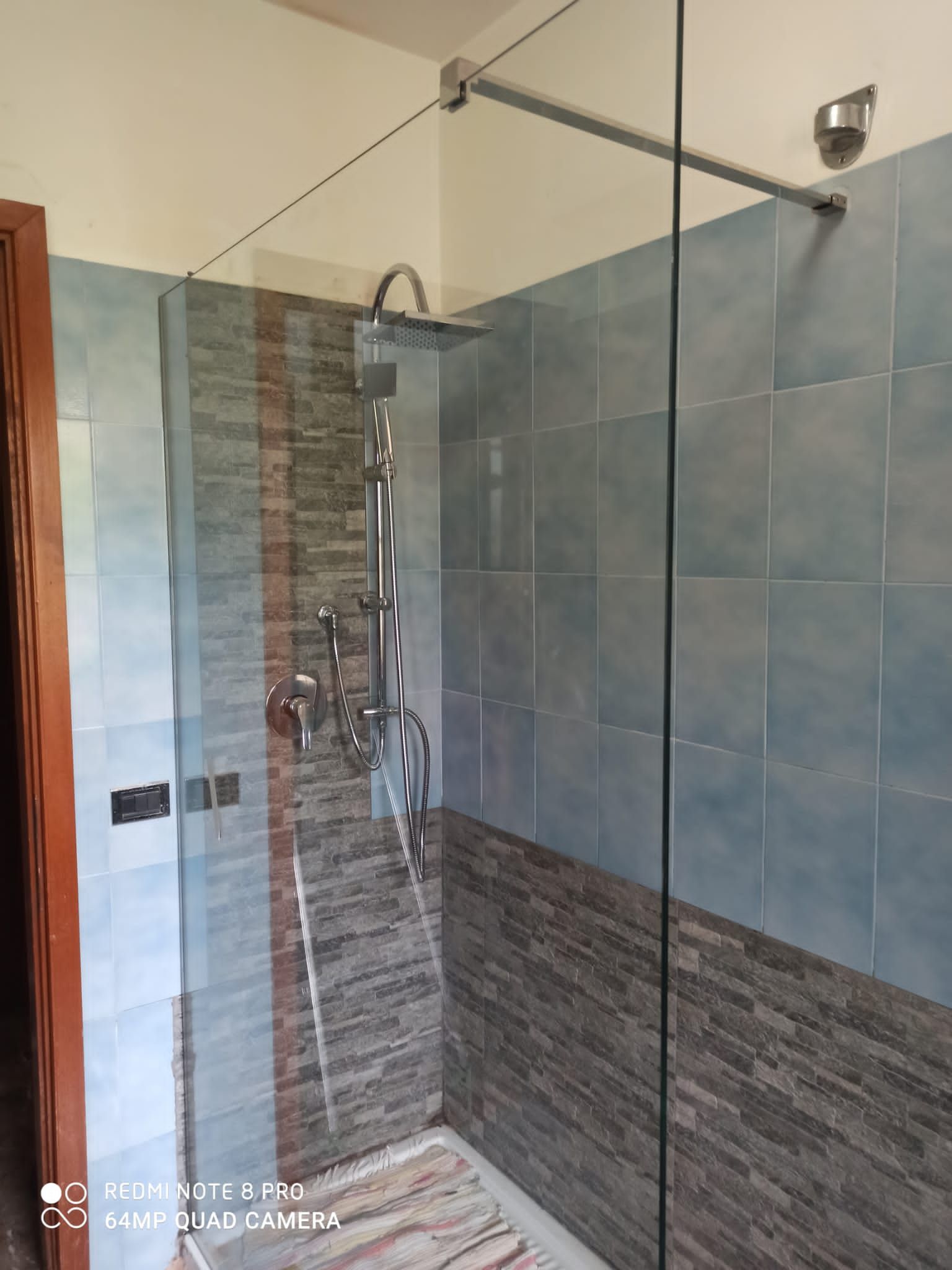 Box doccia con pannelli in vetro trasparente; acqua che scende a cascata.
