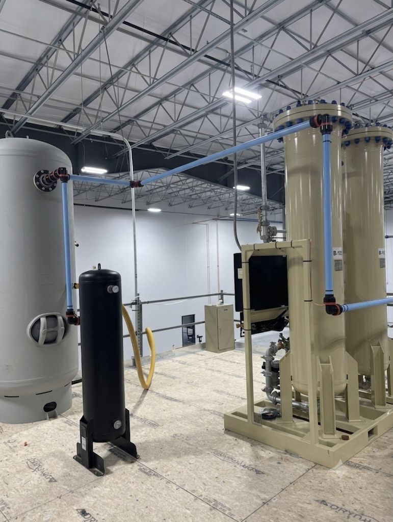 Industrial facility with large tanks, beige piping, and overhead steel trusses in a spacious room