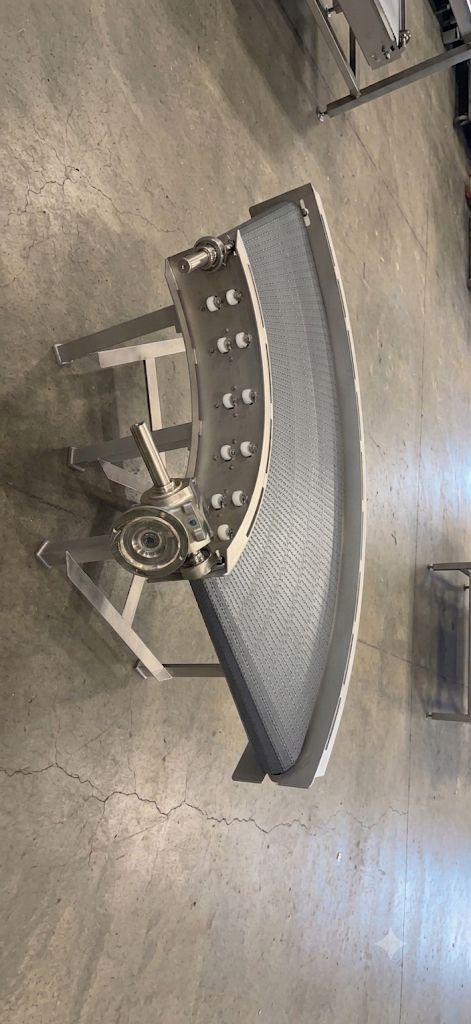 Curved metal industrial part on a concrete floor, viewed from above.
