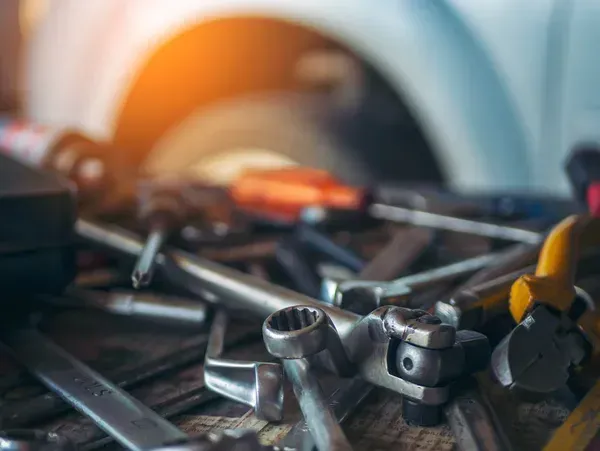 Scattered metal tools on a workbench with a blurred orange and blue background