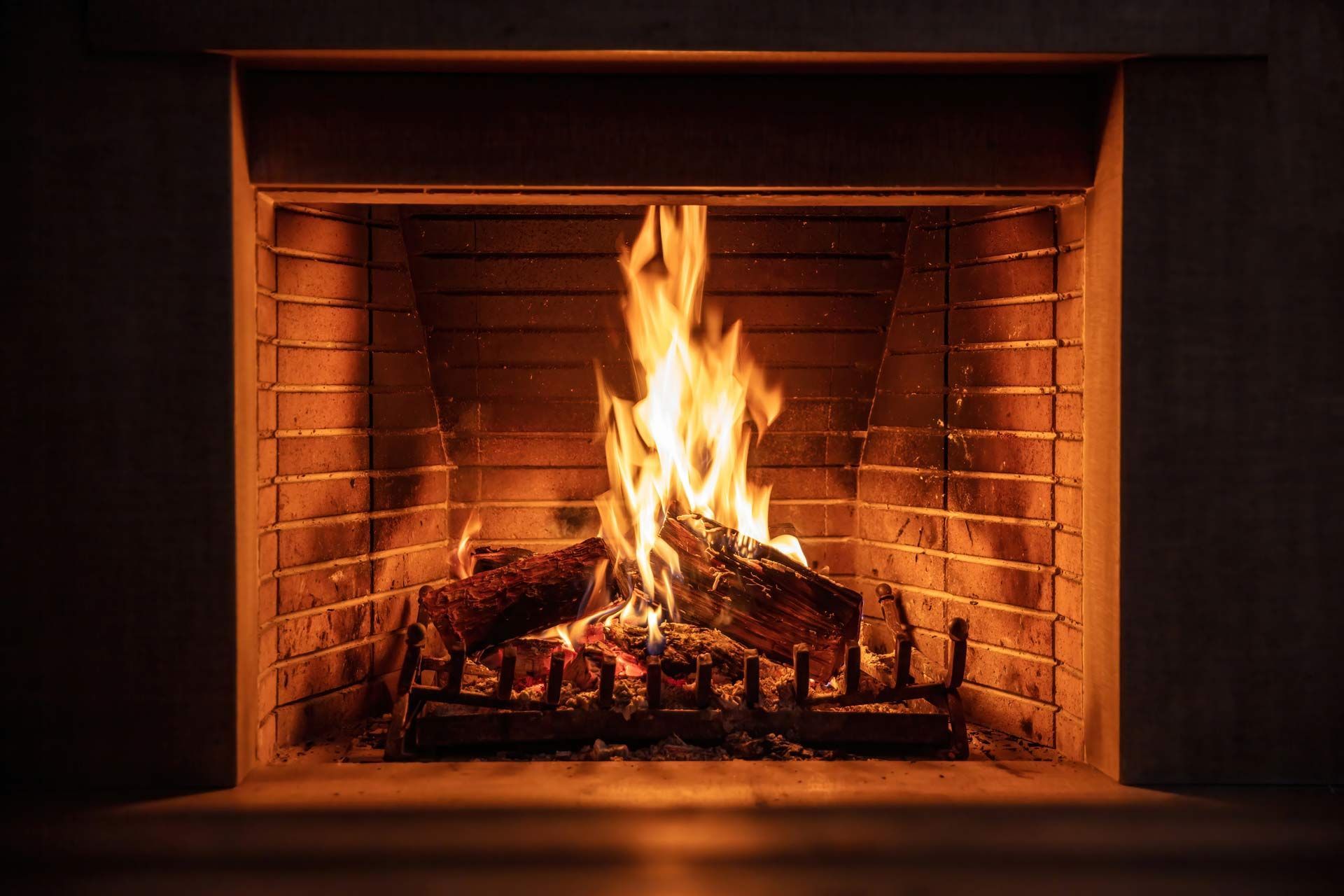Cozy fireplace with bright flames and glowing logs inside a brick hearth