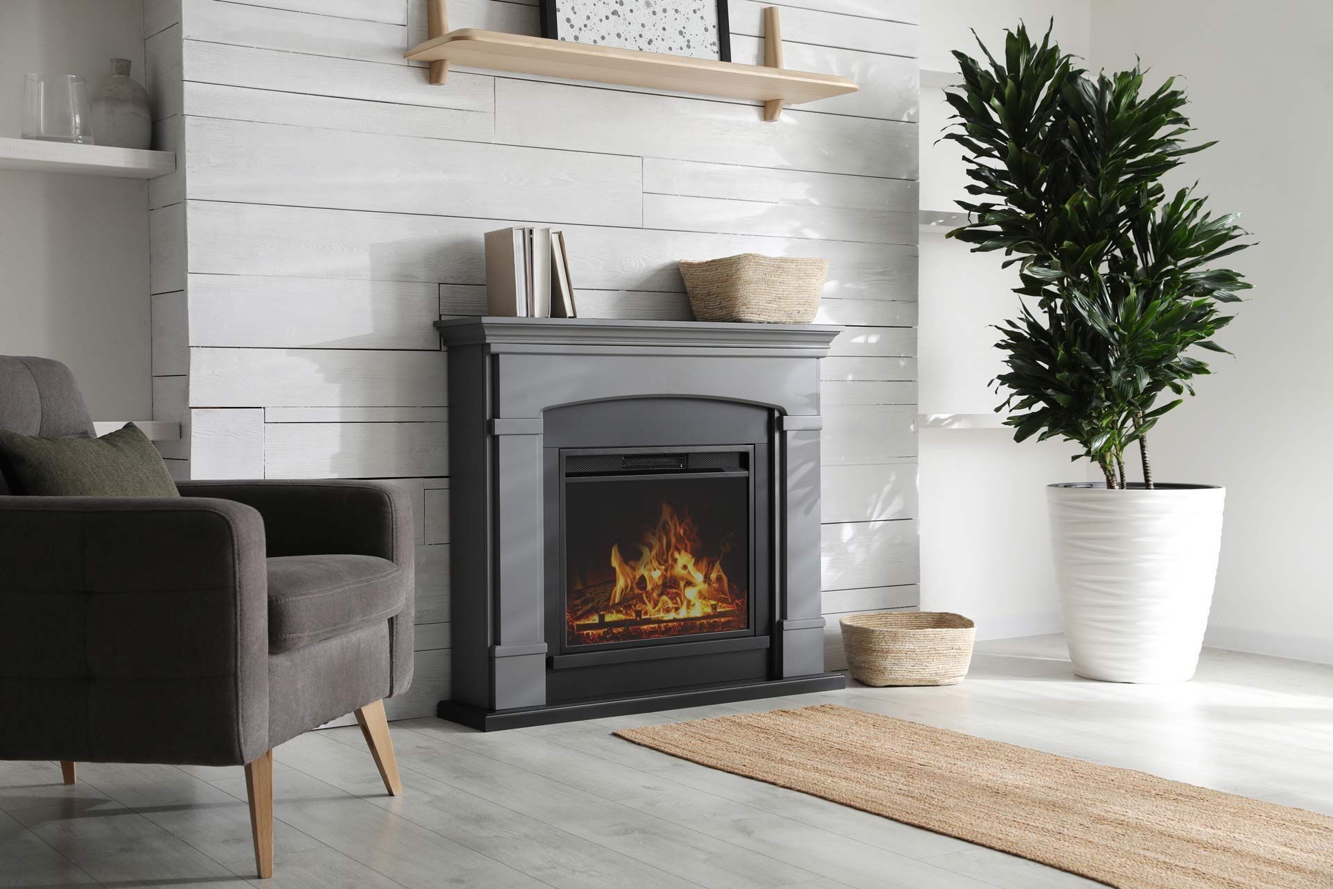 Modern living room with gray armchair, electric fireplace, white brick wall, and potted plant