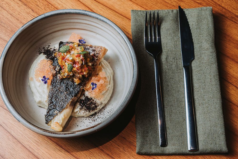 Exquisite gourmet dish with grilled fish and fresh vegetables, served at Overo Iguazu's jungle restaurant.