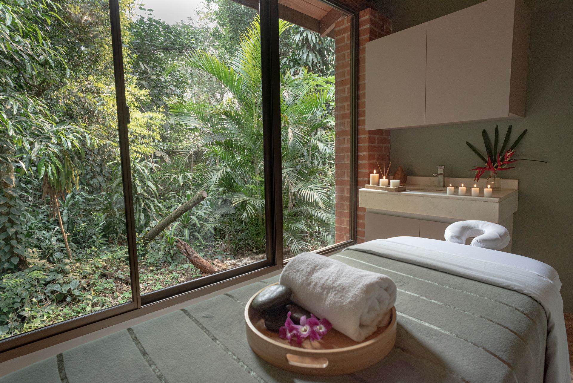 Sala de masajes con mesa y vista panorámica a la selva de Iguazú, parte de la experiencia de spa en Overo Iguazú.