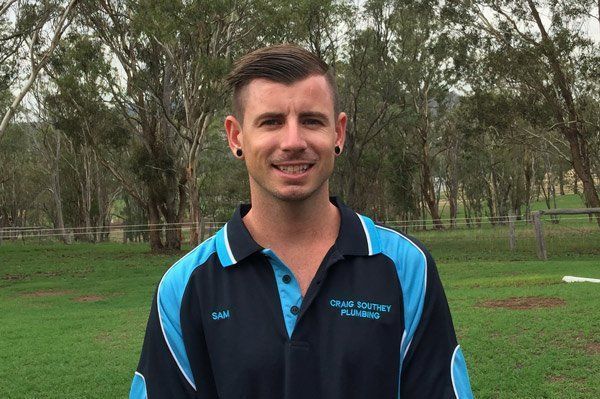 A man in a blue and black shirt is standing in a field.