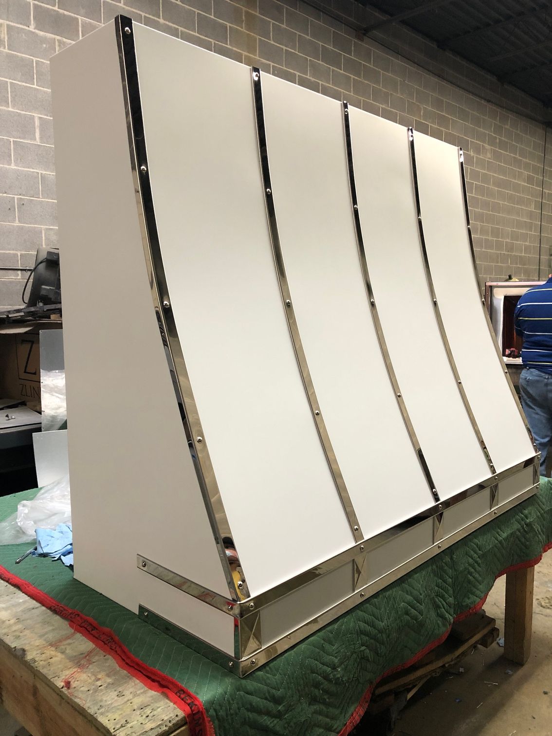 A white cabinet with stainless steel trim is sitting on top of a wooden table.